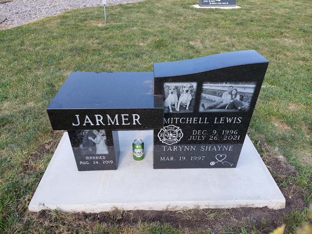 Two black granite gravestones on a concrete base in a cemetery lawn, one marked JARMER, one MEDLIN LEWIS.