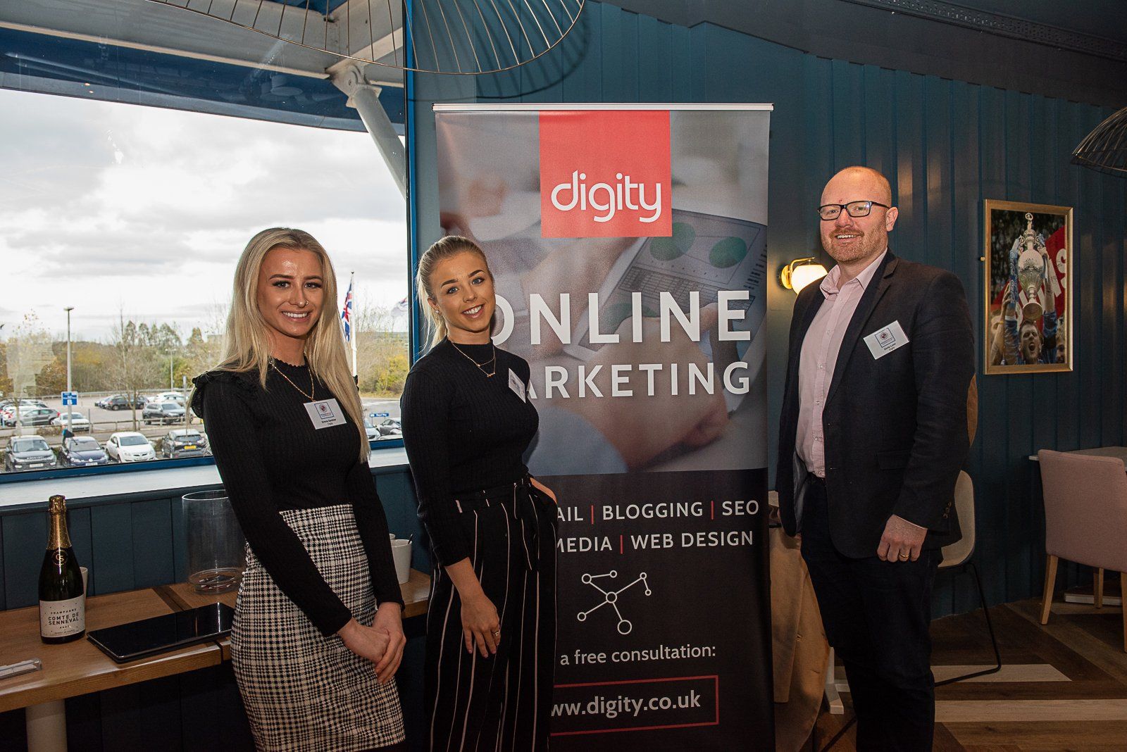 Three people are standing in front of a sign that says online marketing.