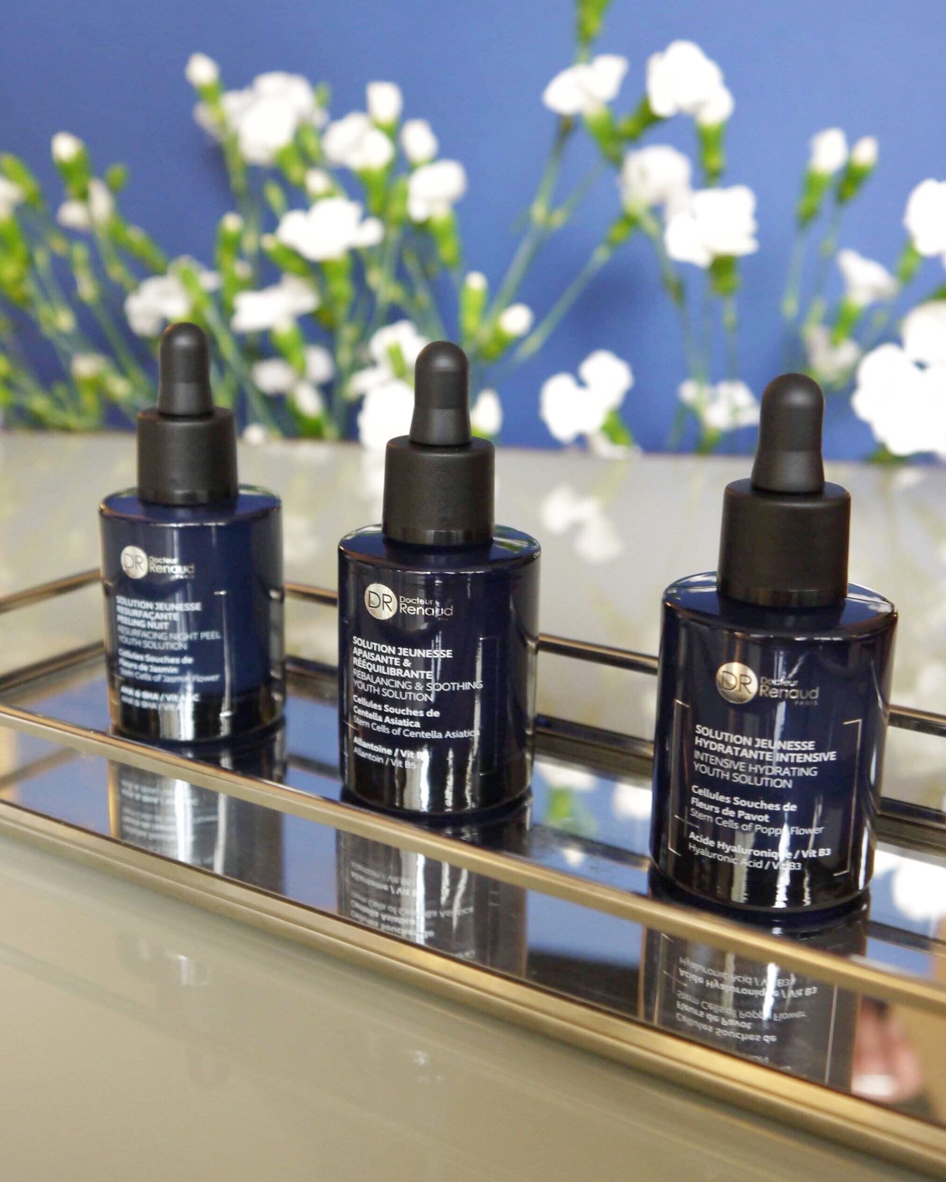 Drie flessen lotion staan ​​op een spiegelend dienblad.