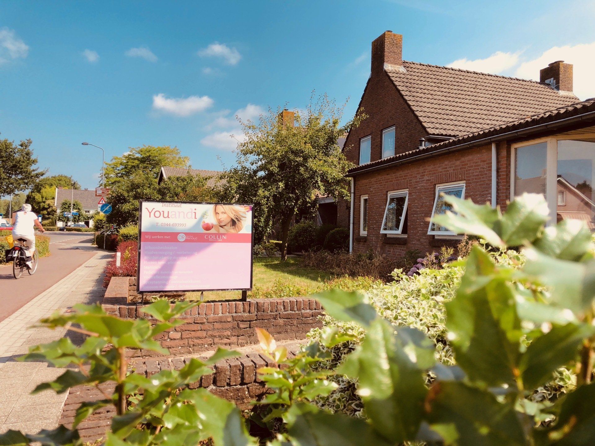 Een bakstenen huis met een bord ervoor.