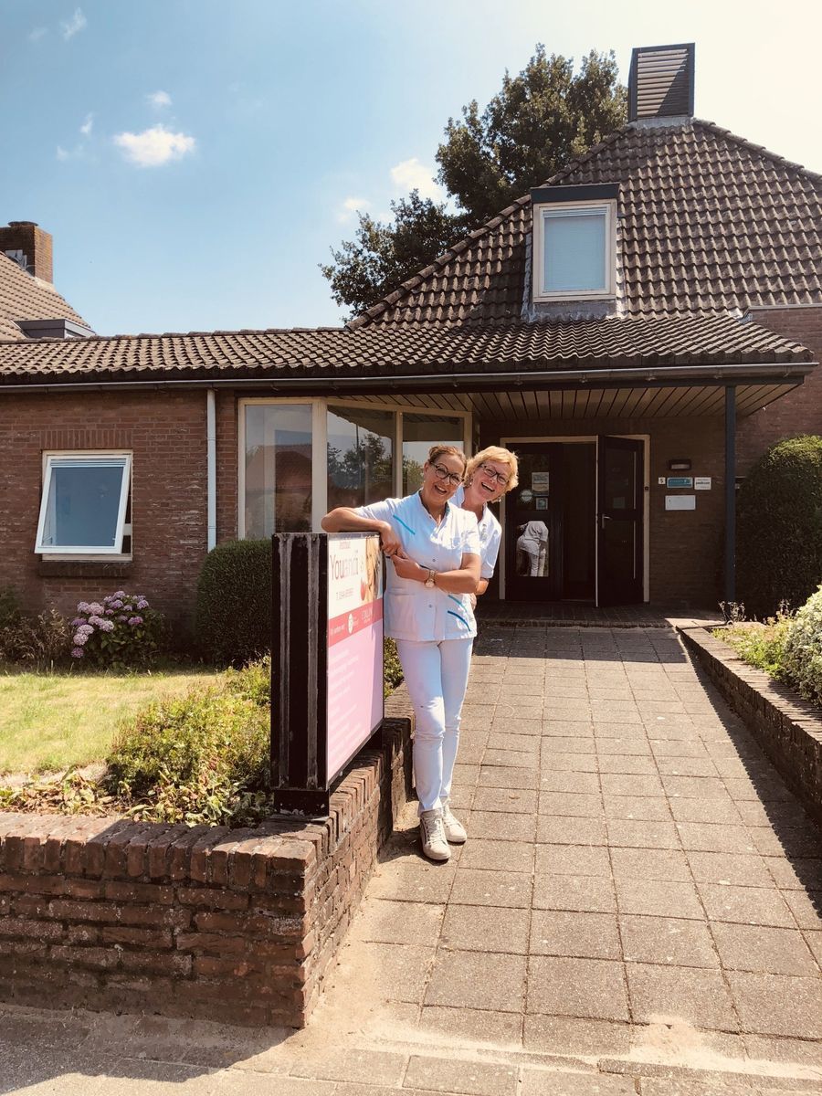 Twee verpleegsters poseren voor een foto voor een gebouw.