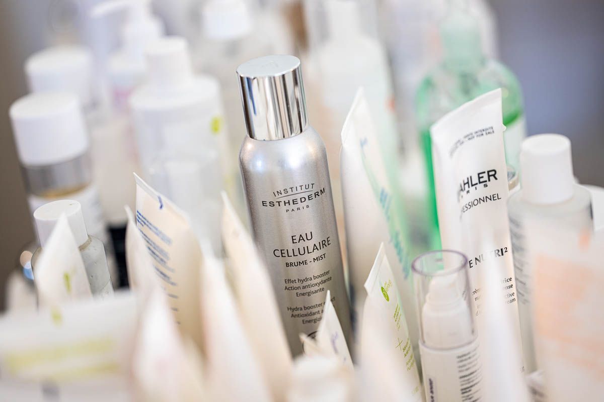 Er staan een aantal flesjes en tubes met cosmetica op een tafel.