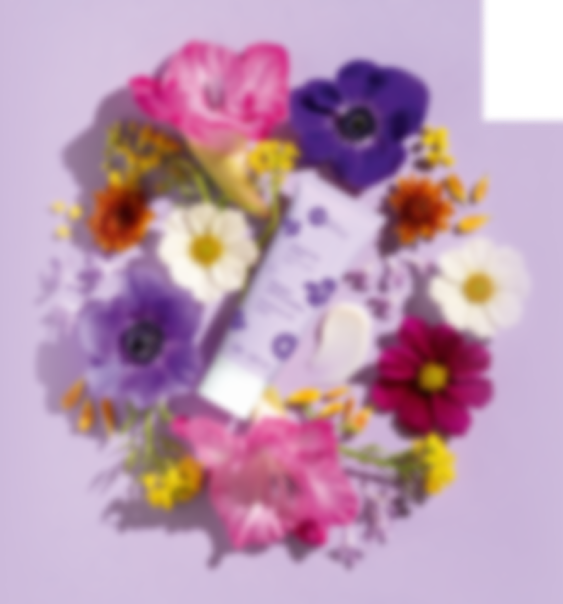 Een fles lotion is omgeven door bloemen op een paarse achtergrond.
