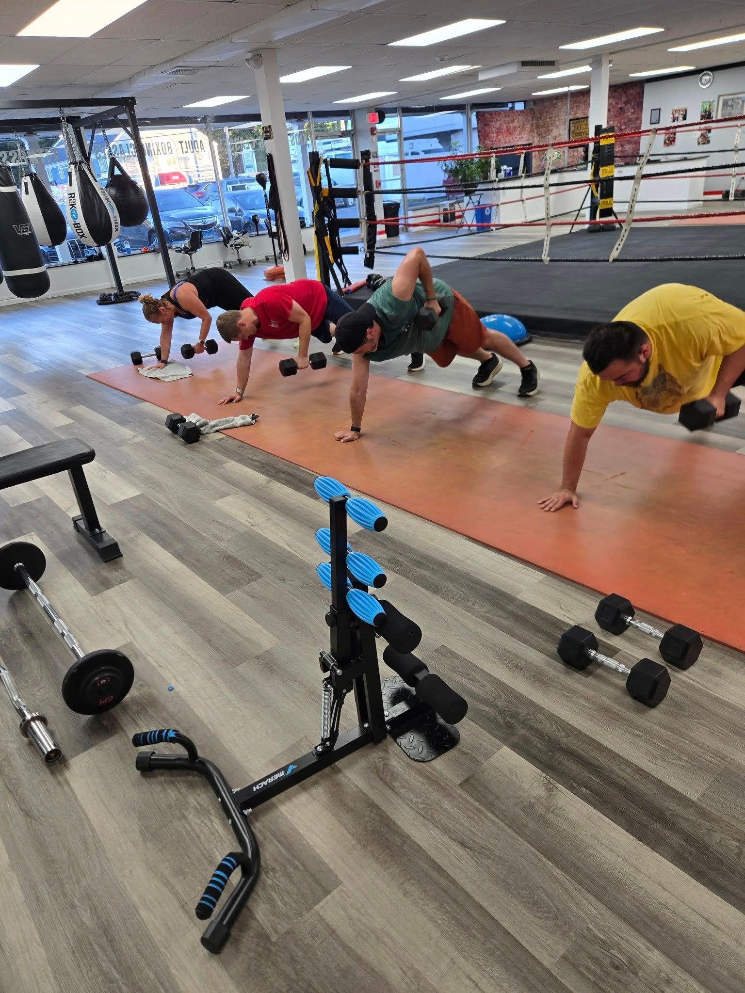 People exercising with weights in a gym. They are doing push-ups and holding dumbbells.