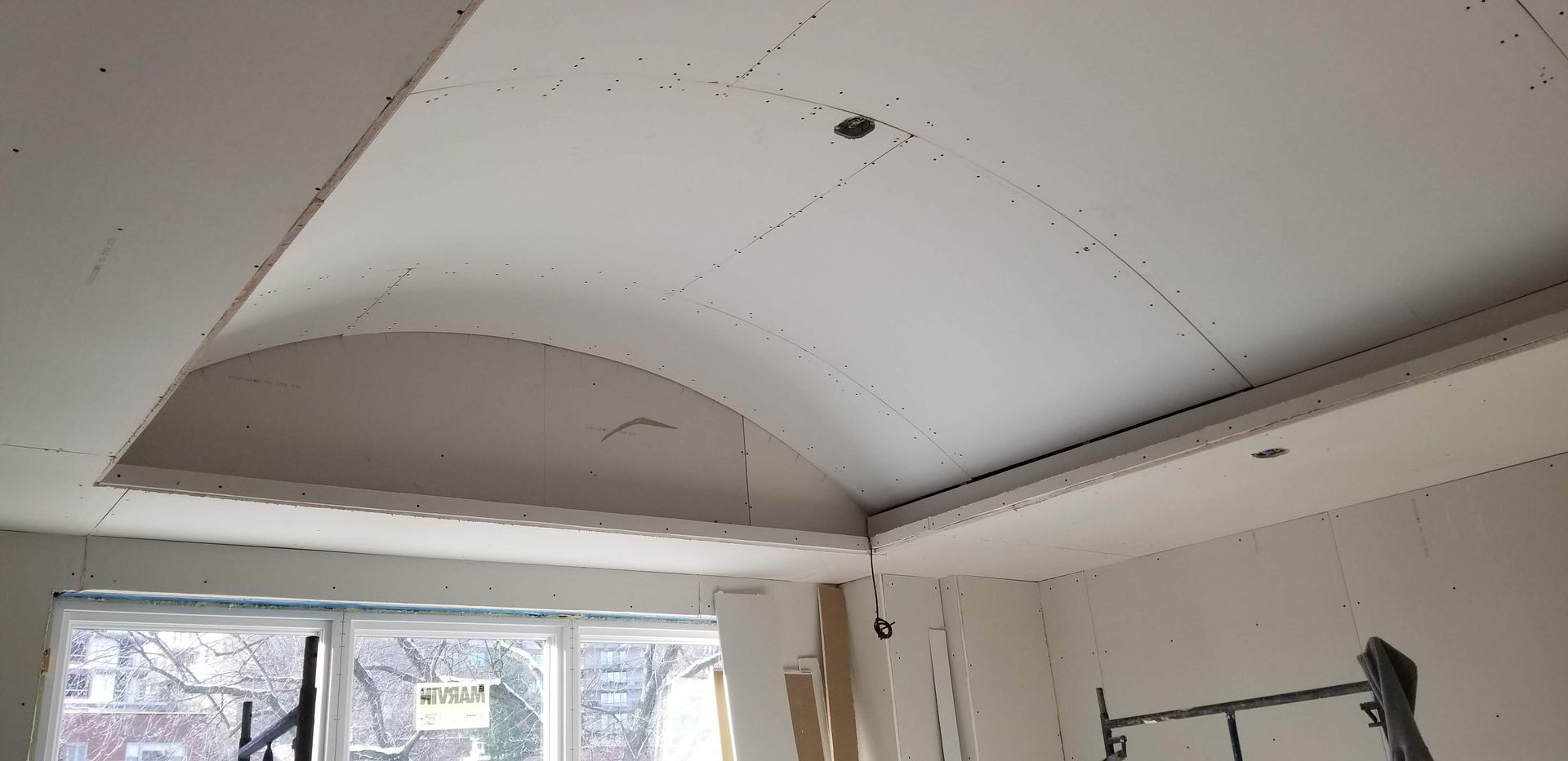 Une pièce avec un plafond en cours de construction et une fenêtre.