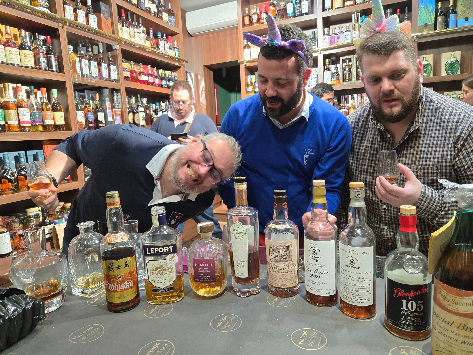 Un groupe d'hommes se tient autour d'une table pleine de bouteilles d'alcool.