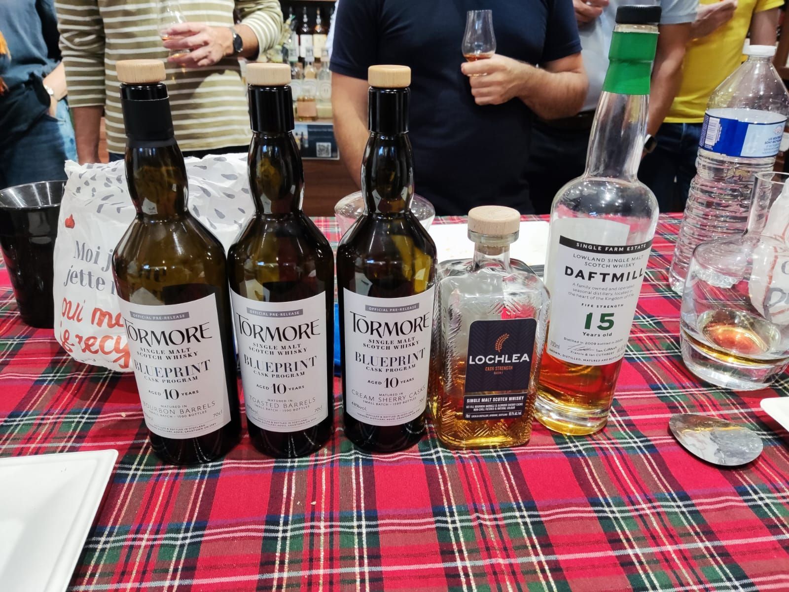 Five whisky bottles on a plaid tablecloth: four 