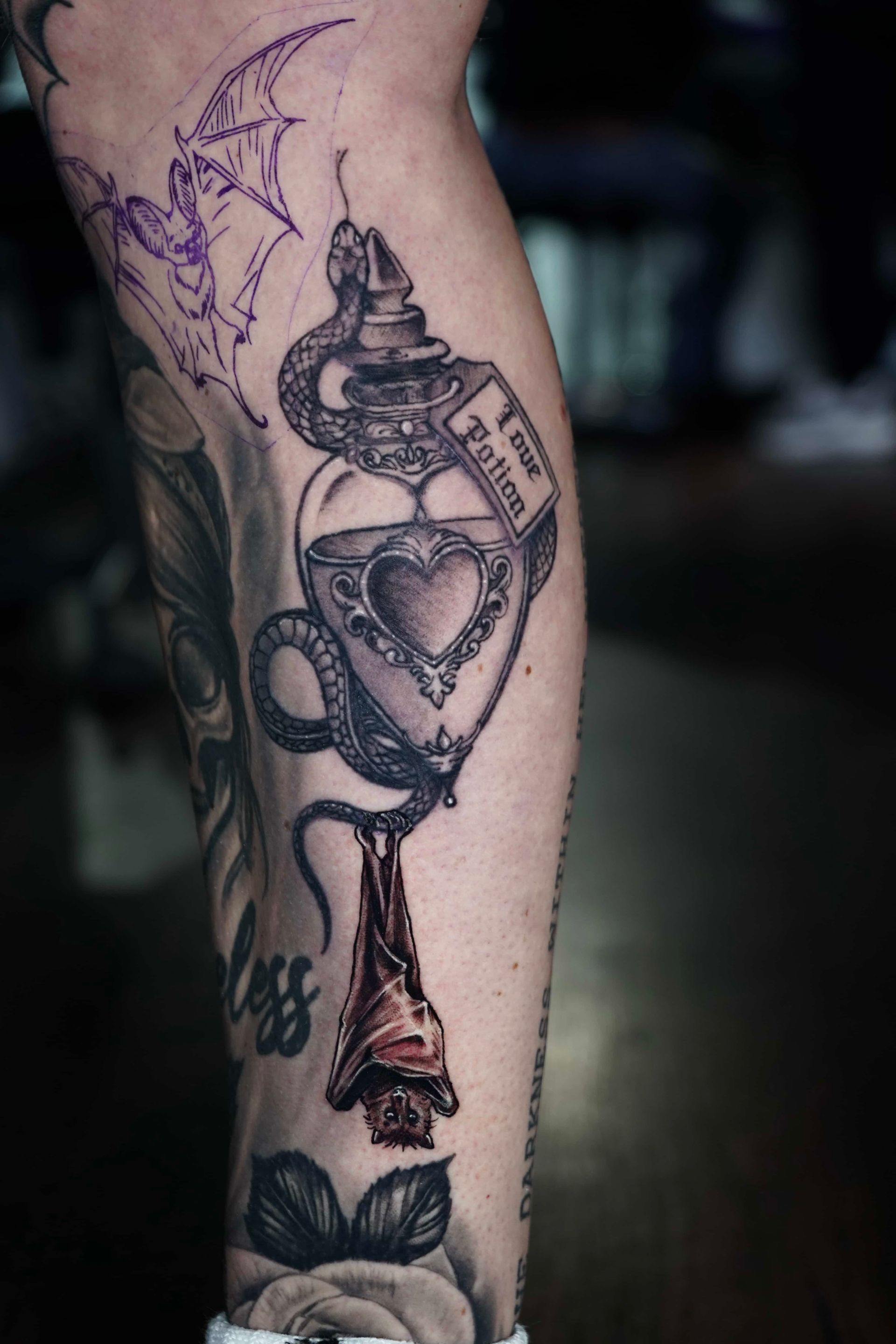 A person’s arm featuring an intricate black-and-grey geometric tattoo sleeve with subtle red accents on a floral element.
