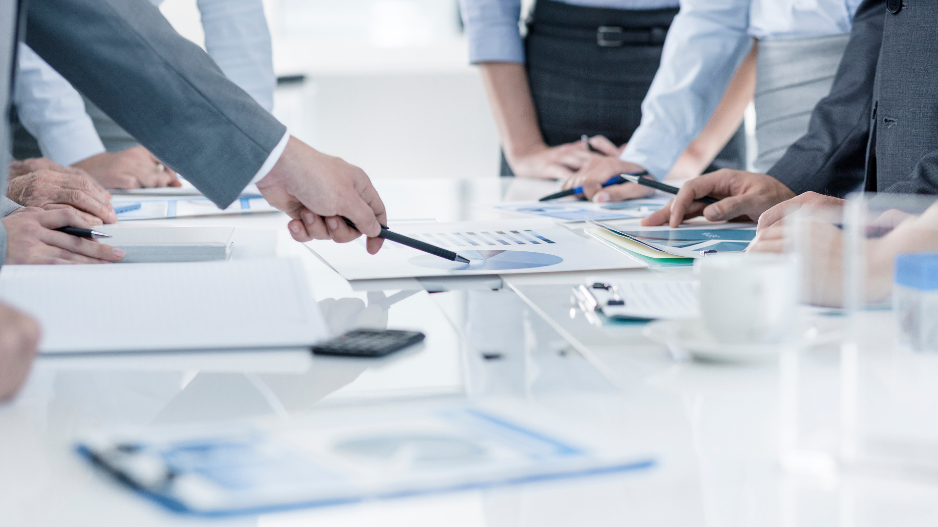 Business meeting: person pointing at a chart on a table with colleagues.