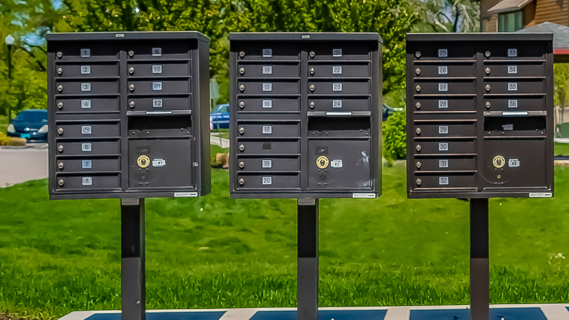 Three black mailboxes on poles in a grassy area, with numbered slots.