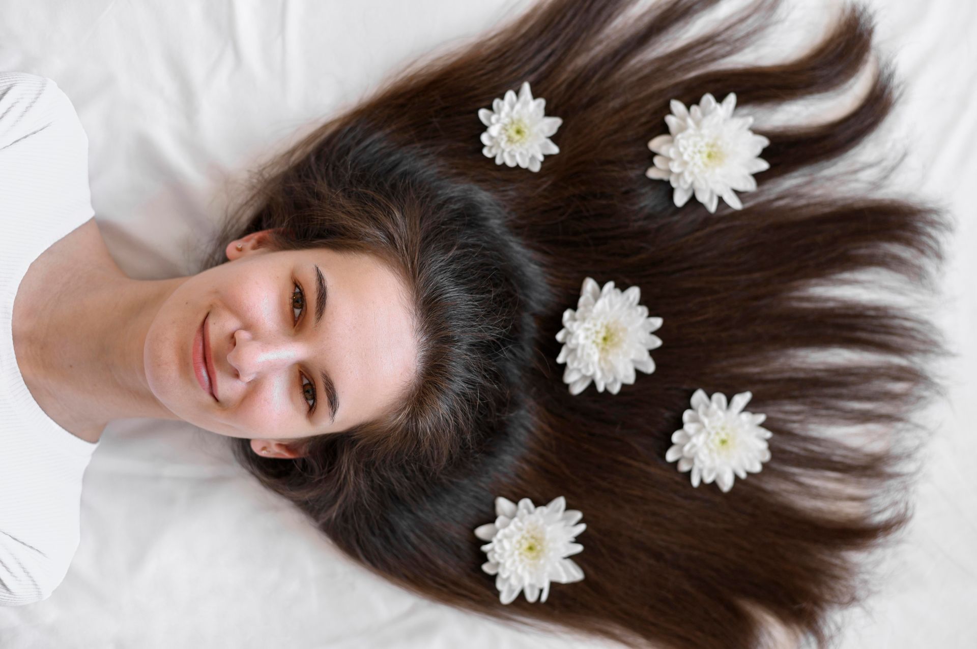 A woman is laying on a bed with flowers in her hair.