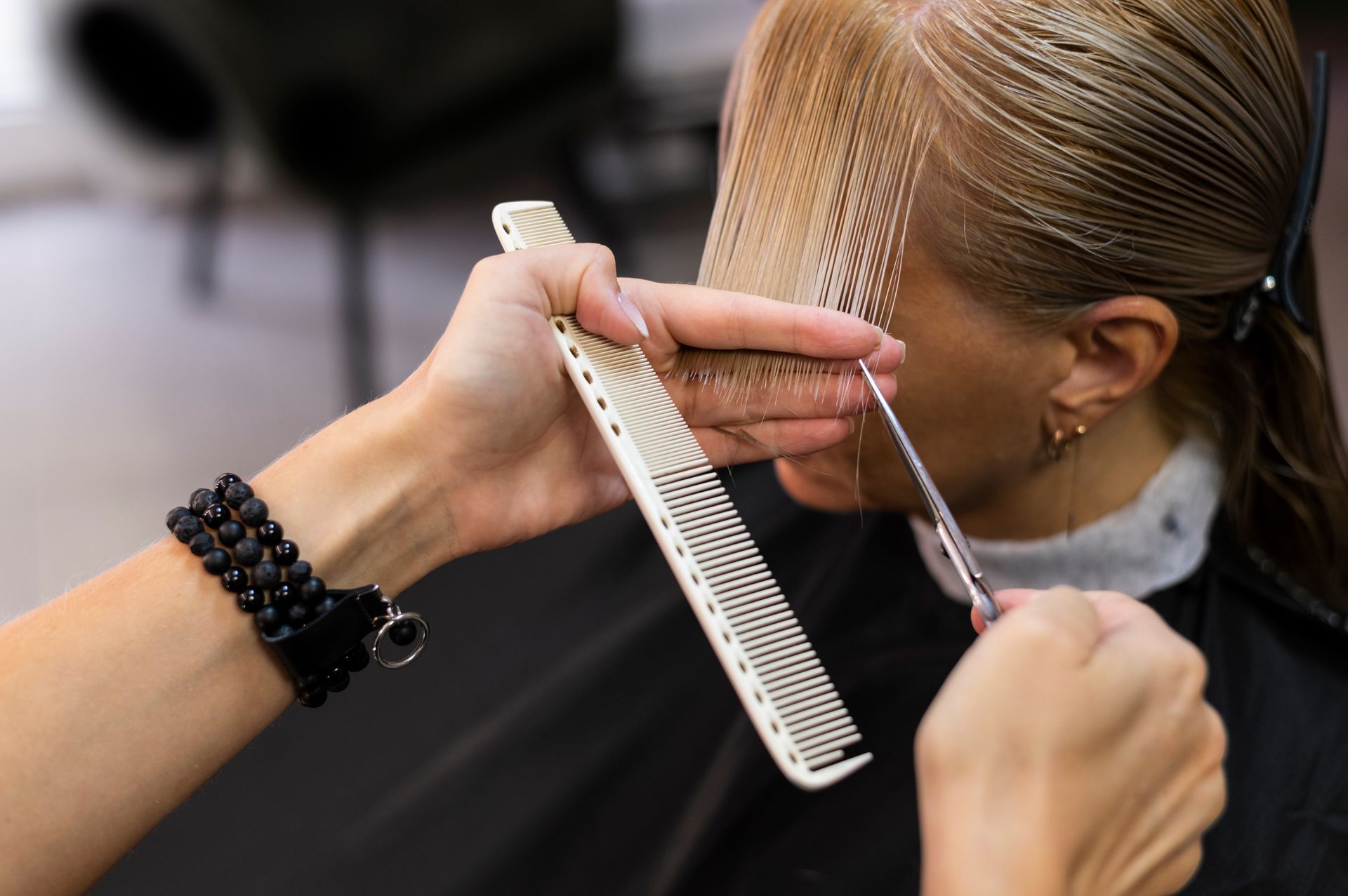 A woman is getting her hair cut by a hairdresser in a salon.