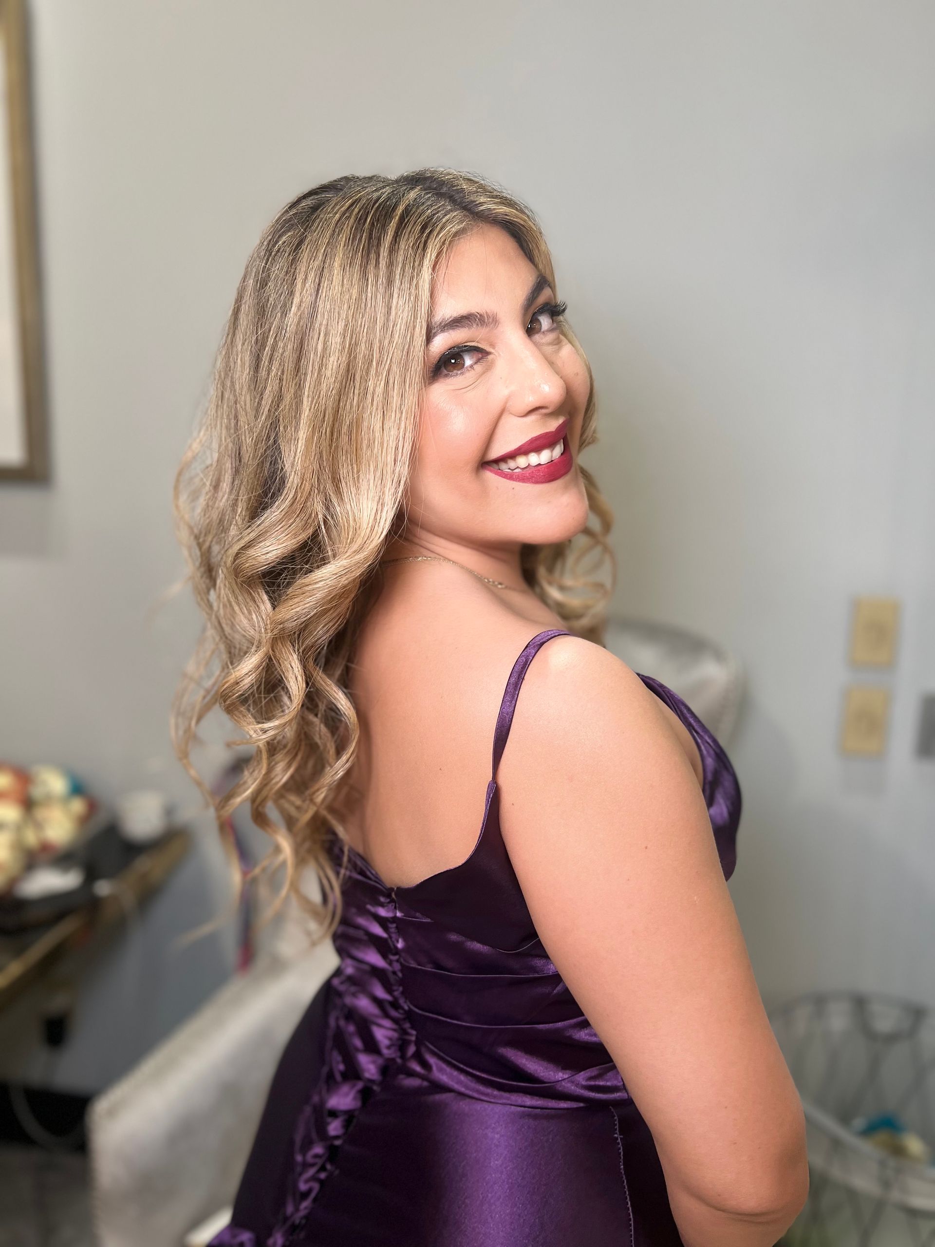 A woman in a purple dress is smiling and looking at the camera.