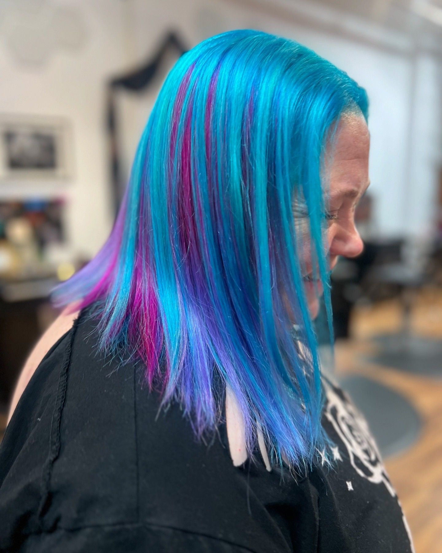 A woman with blue and pink hair is wearing a black shirt.