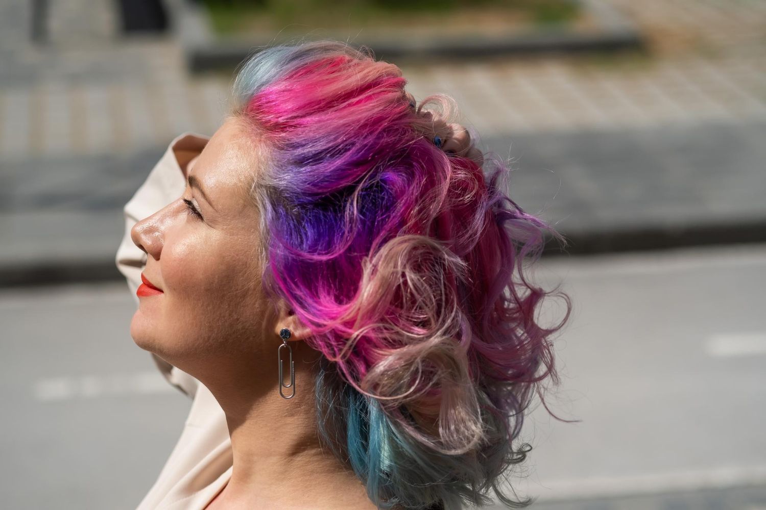 A woman with colorful hair is walking down the street.