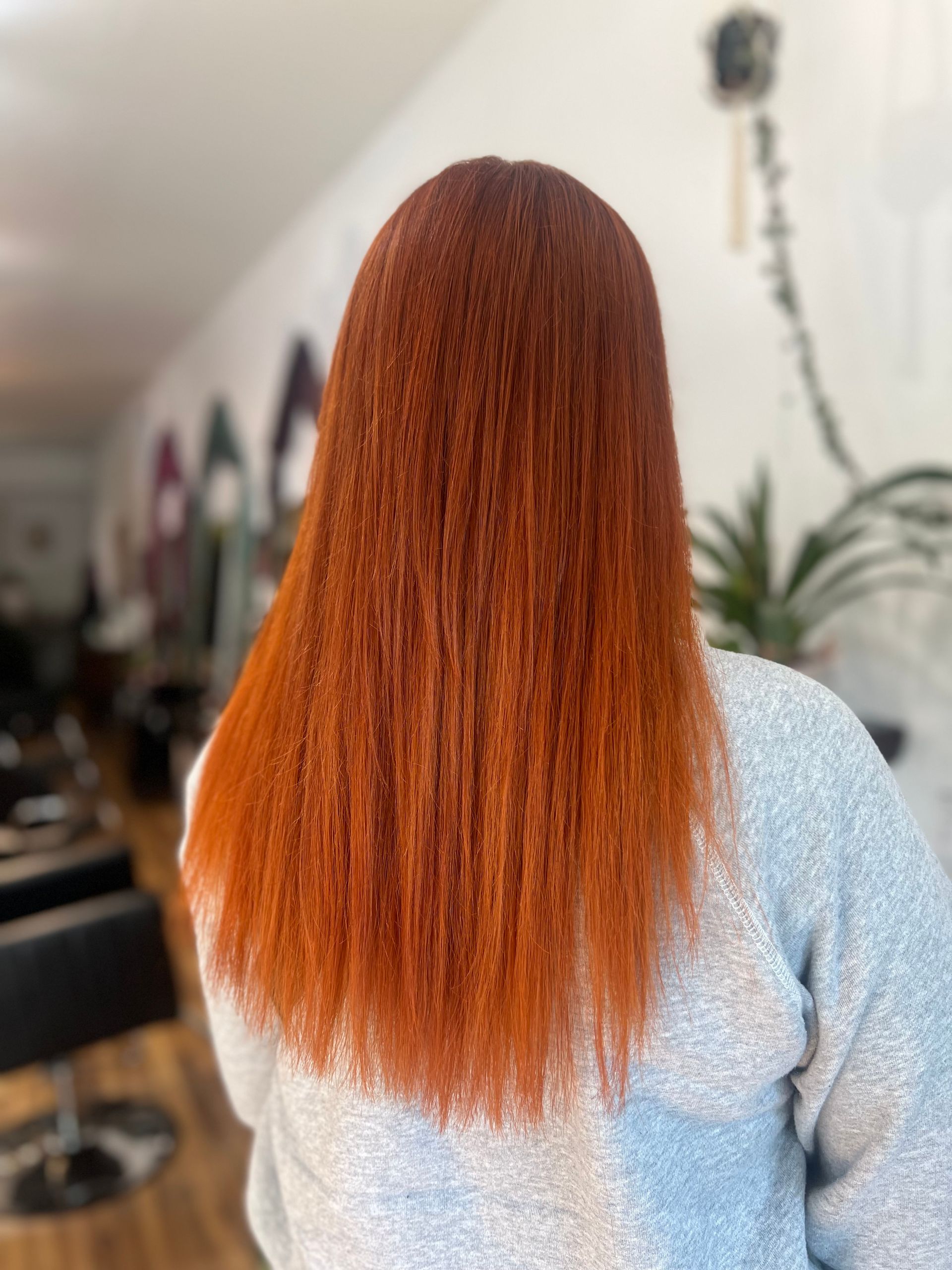A woman with long red hair is standing in a salon.