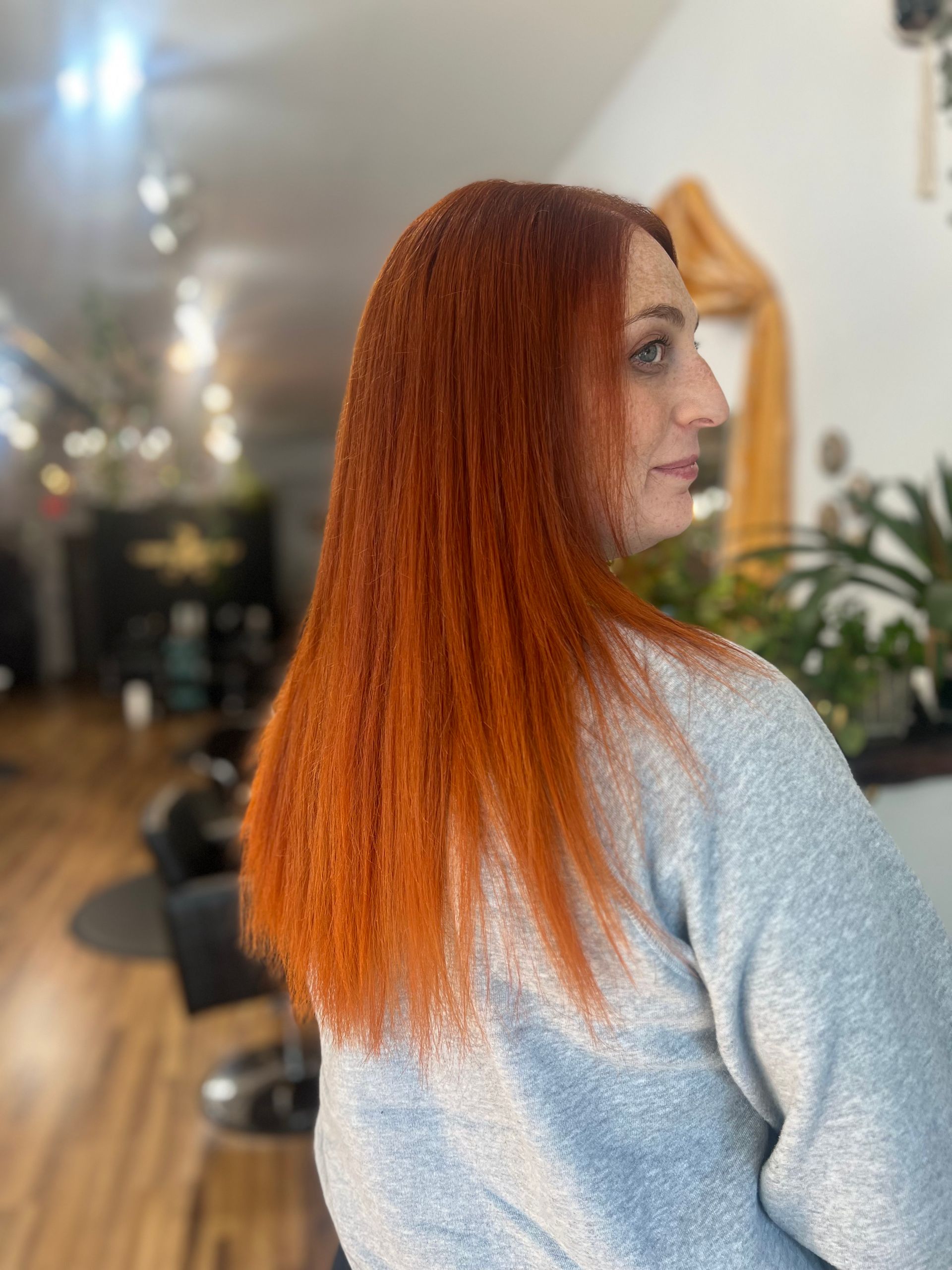 A woman with long red hair is sitting in a chair in a salon.