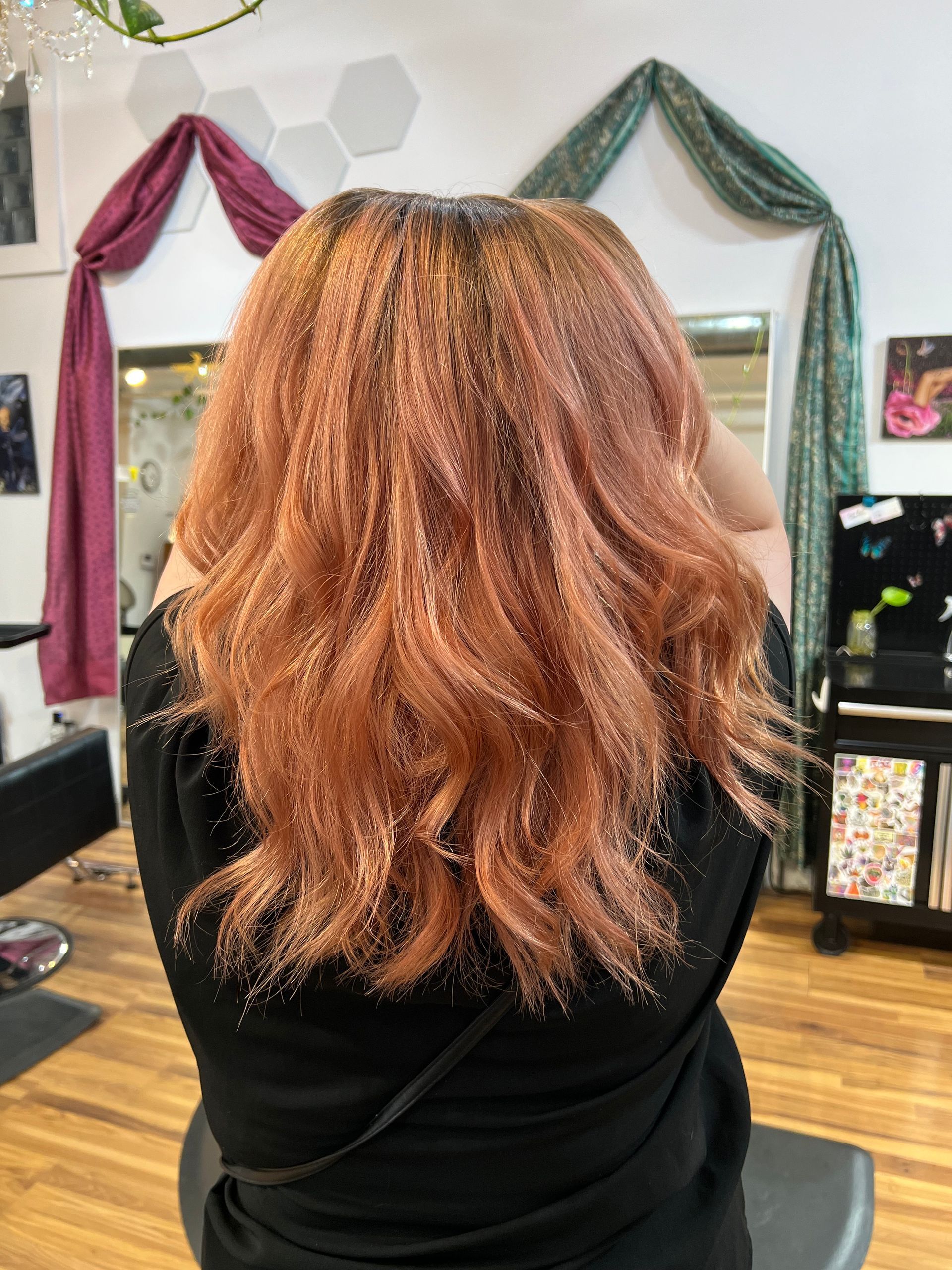 A woman with long red hair is sitting in a chair in a salon.
