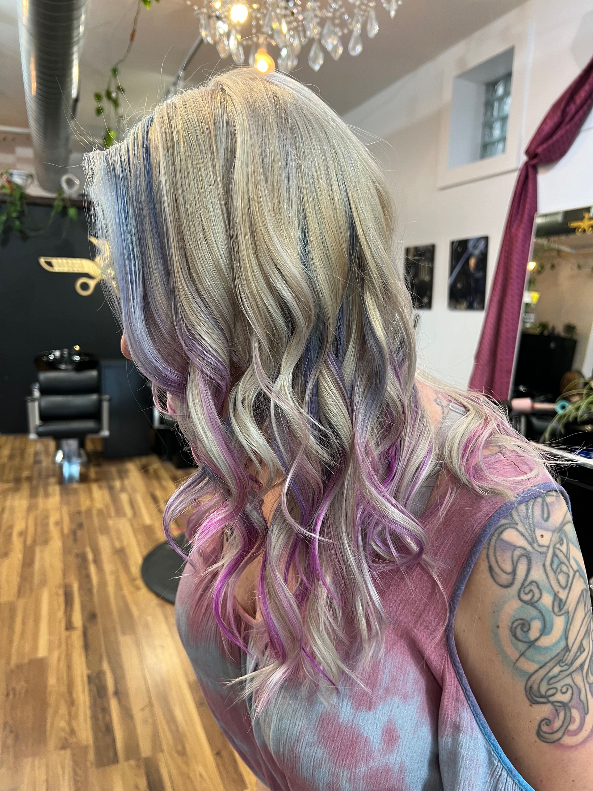 A woman with purple and white hair is standing in a salon.