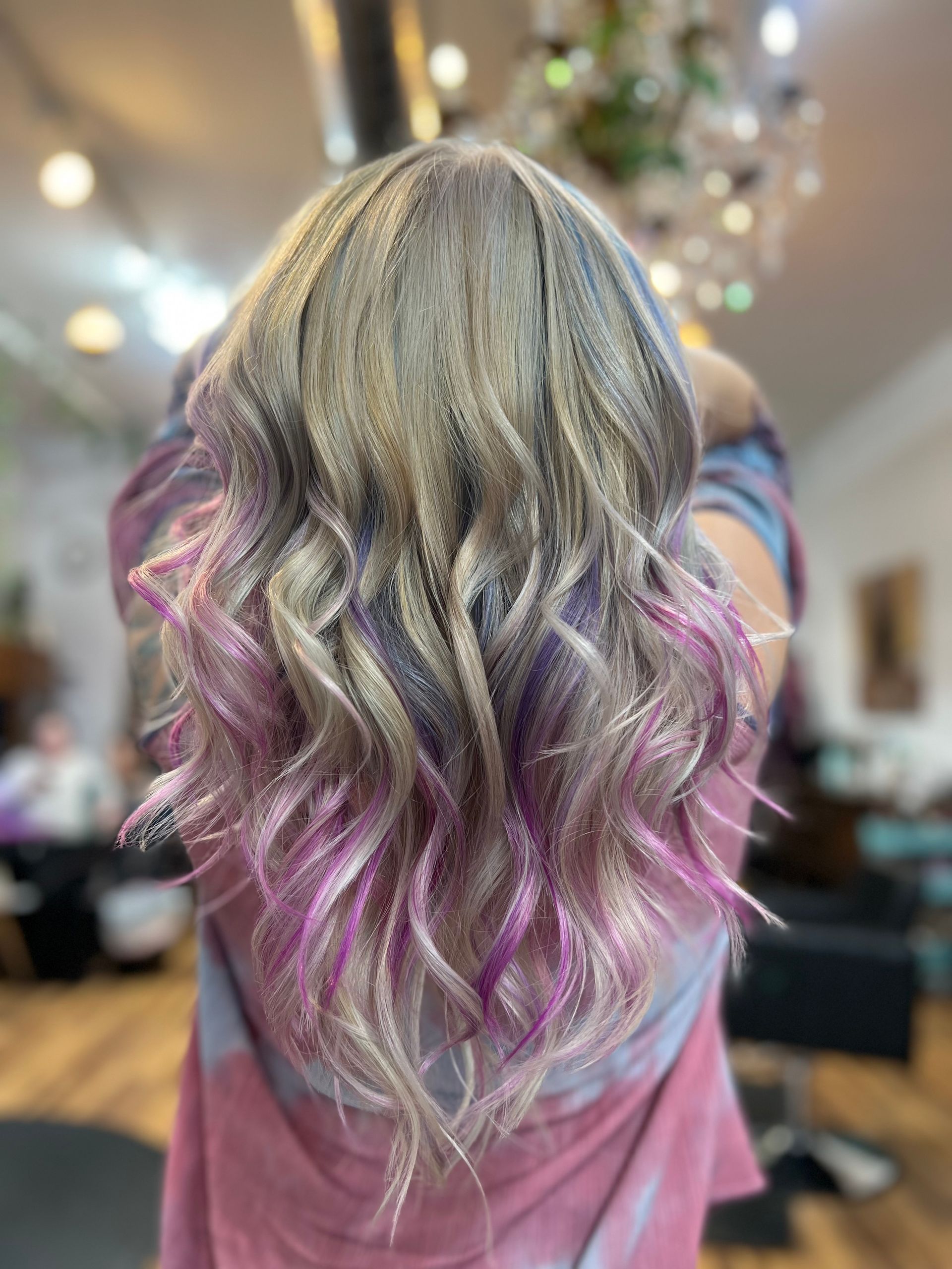 A woman with blonde and pink hair is standing in a salon.