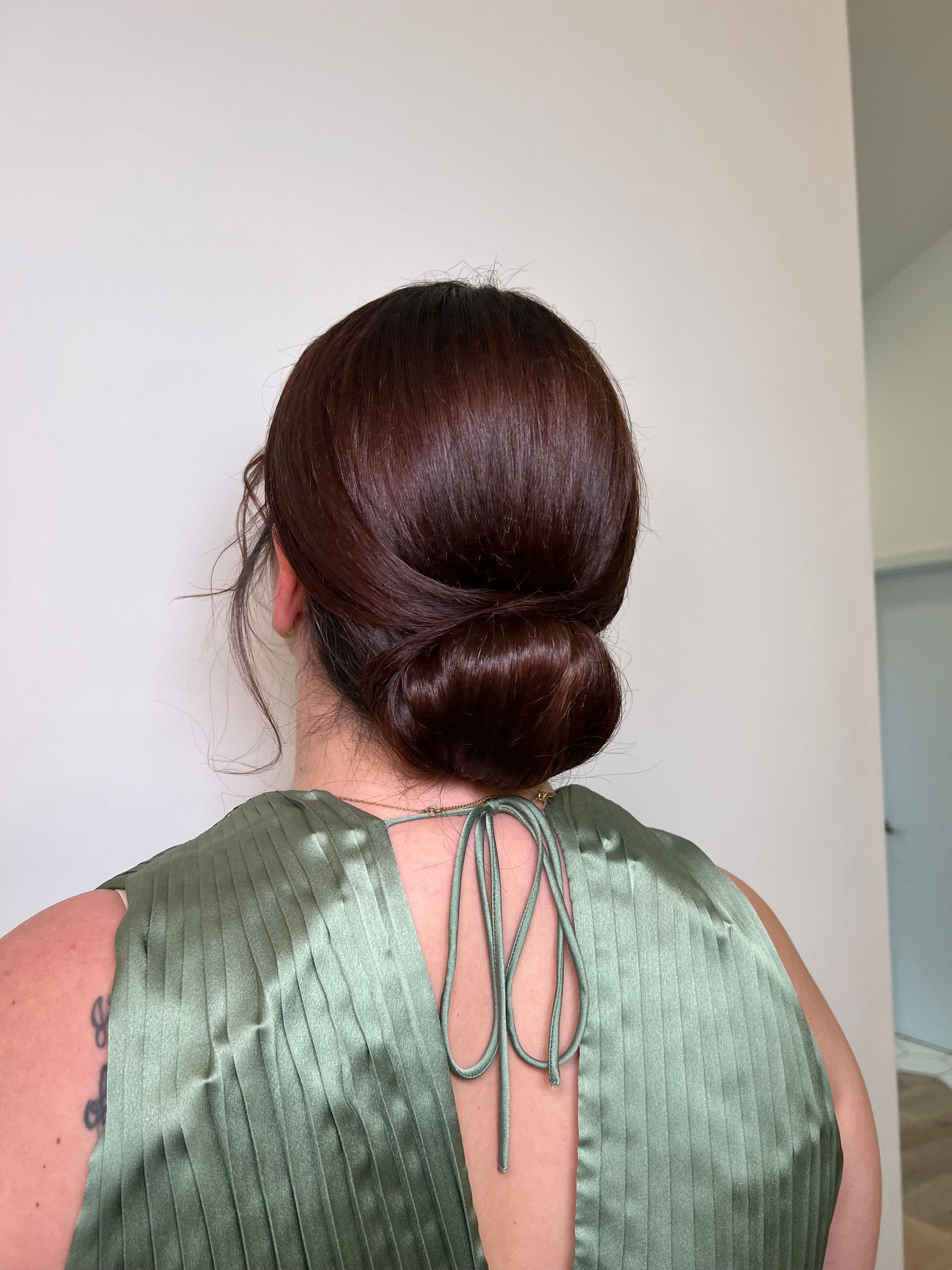 A woman is wearing a green dress and has her hair in a bun.
