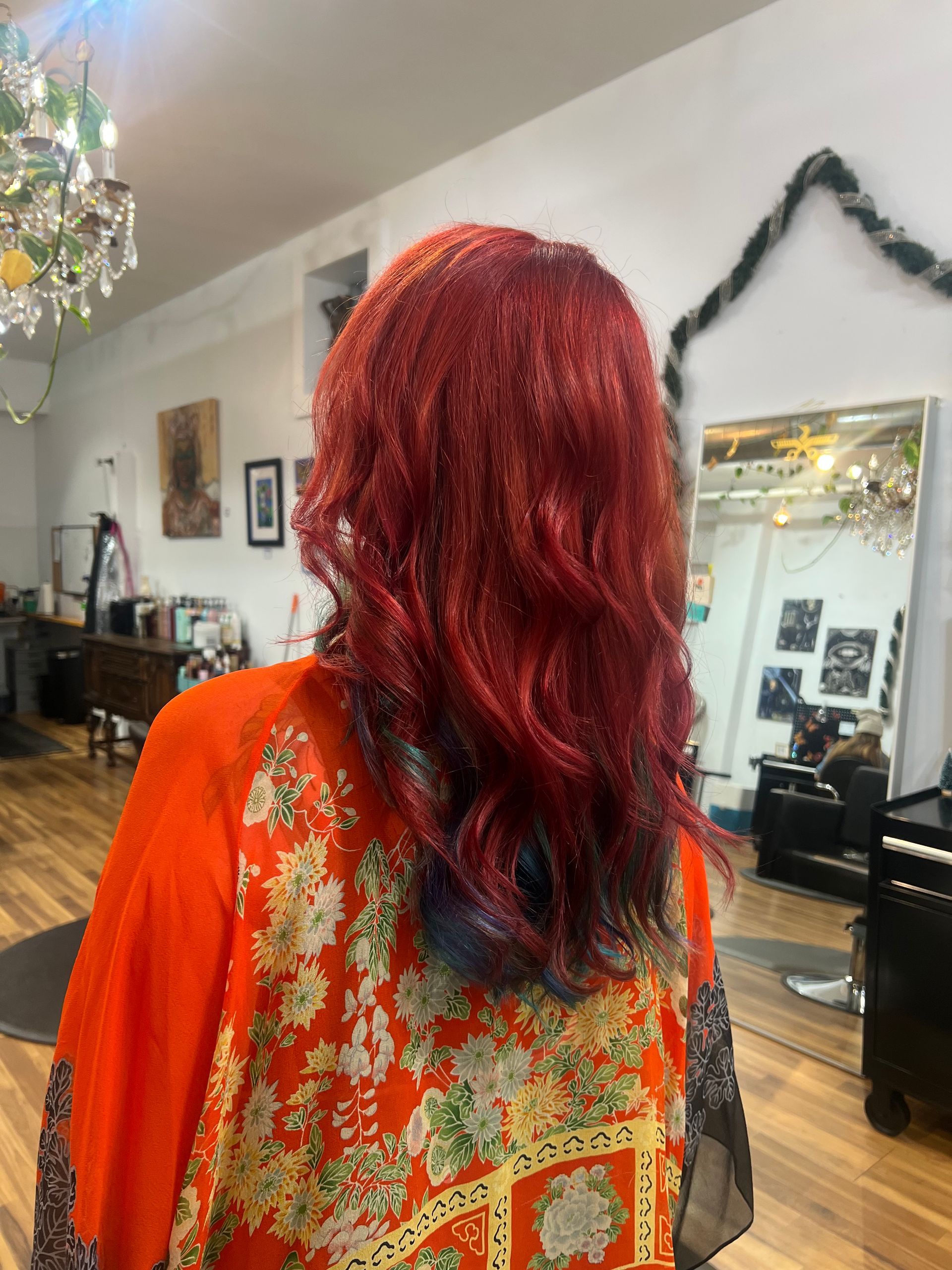 A woman with red hair is standing in a salon.