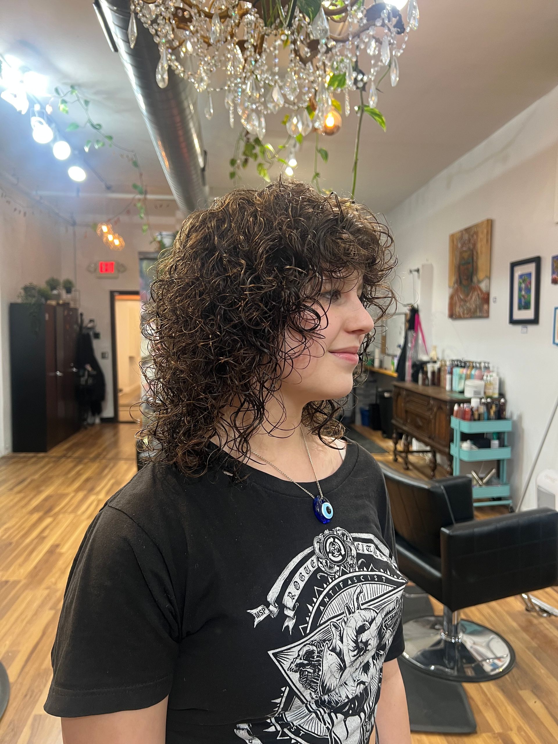 A woman with curly hair is sitting in a chair in a salon.