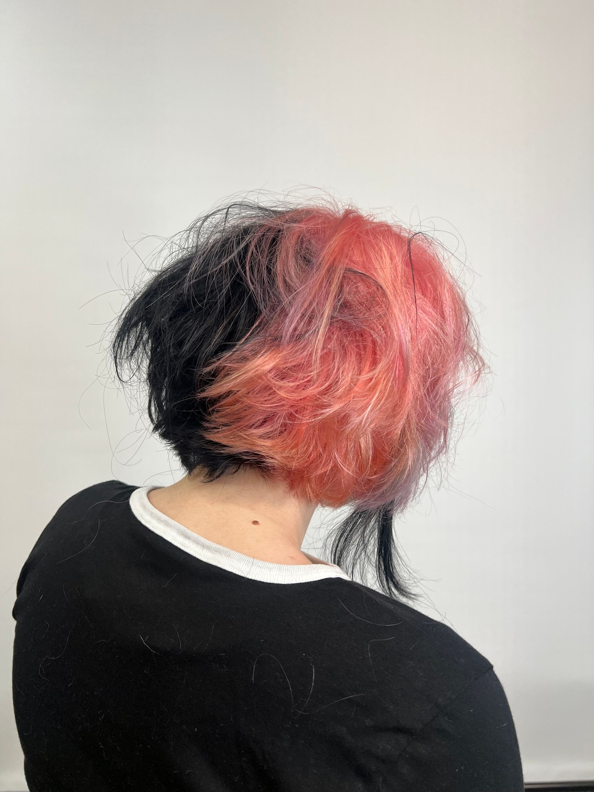A woman with black and pink hair is wearing a black shirt.