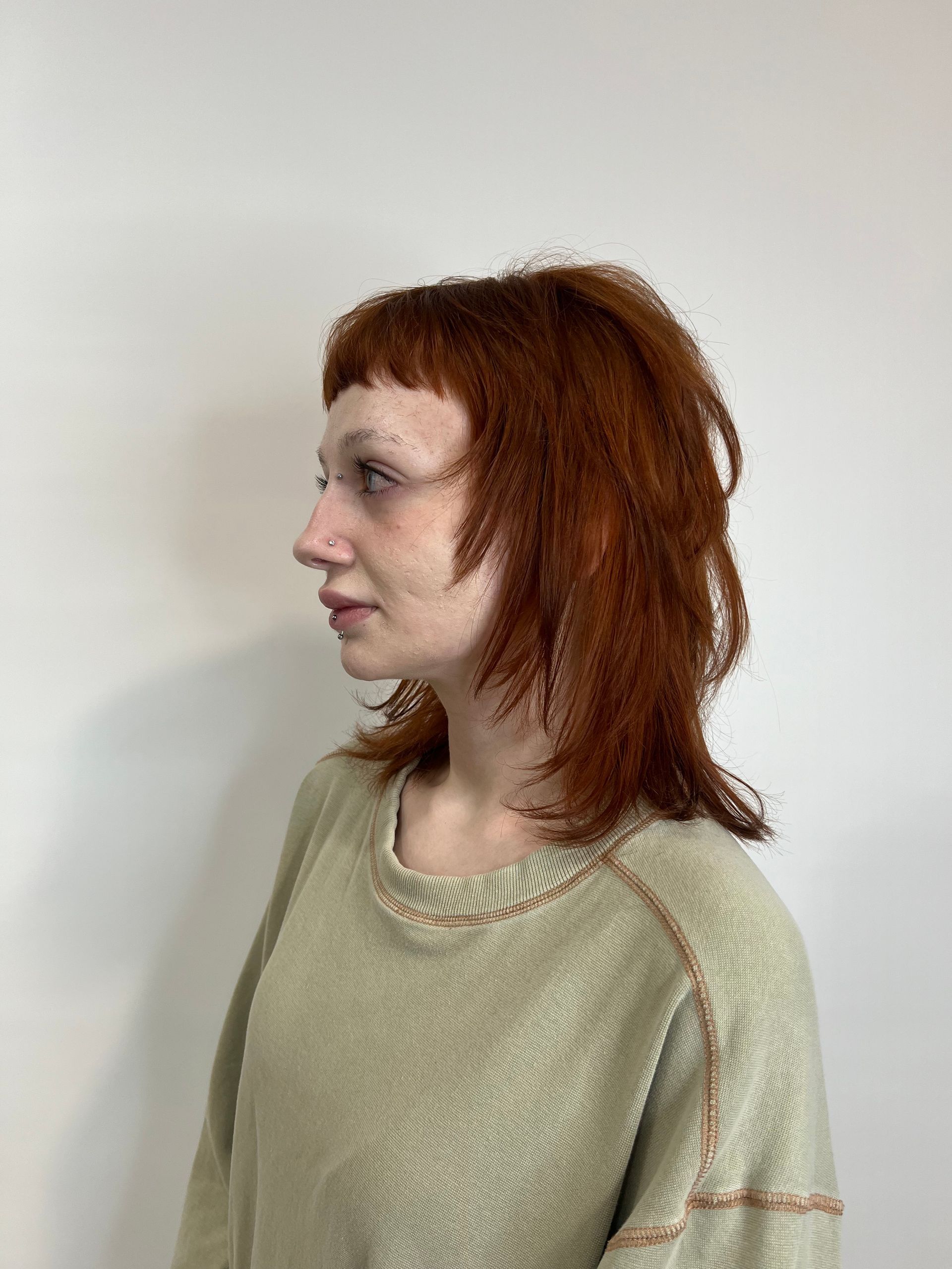 A woman with red hair is wearing a green sweater.