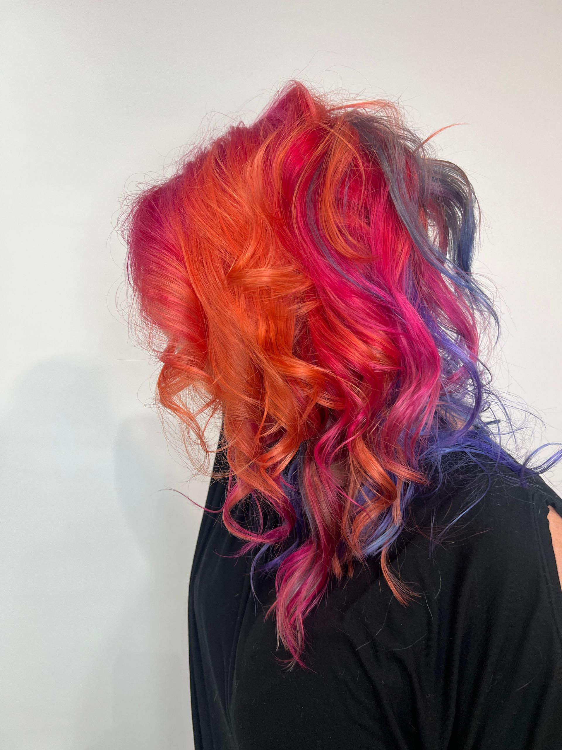 A woman with colorful hair is wearing a black shirt.