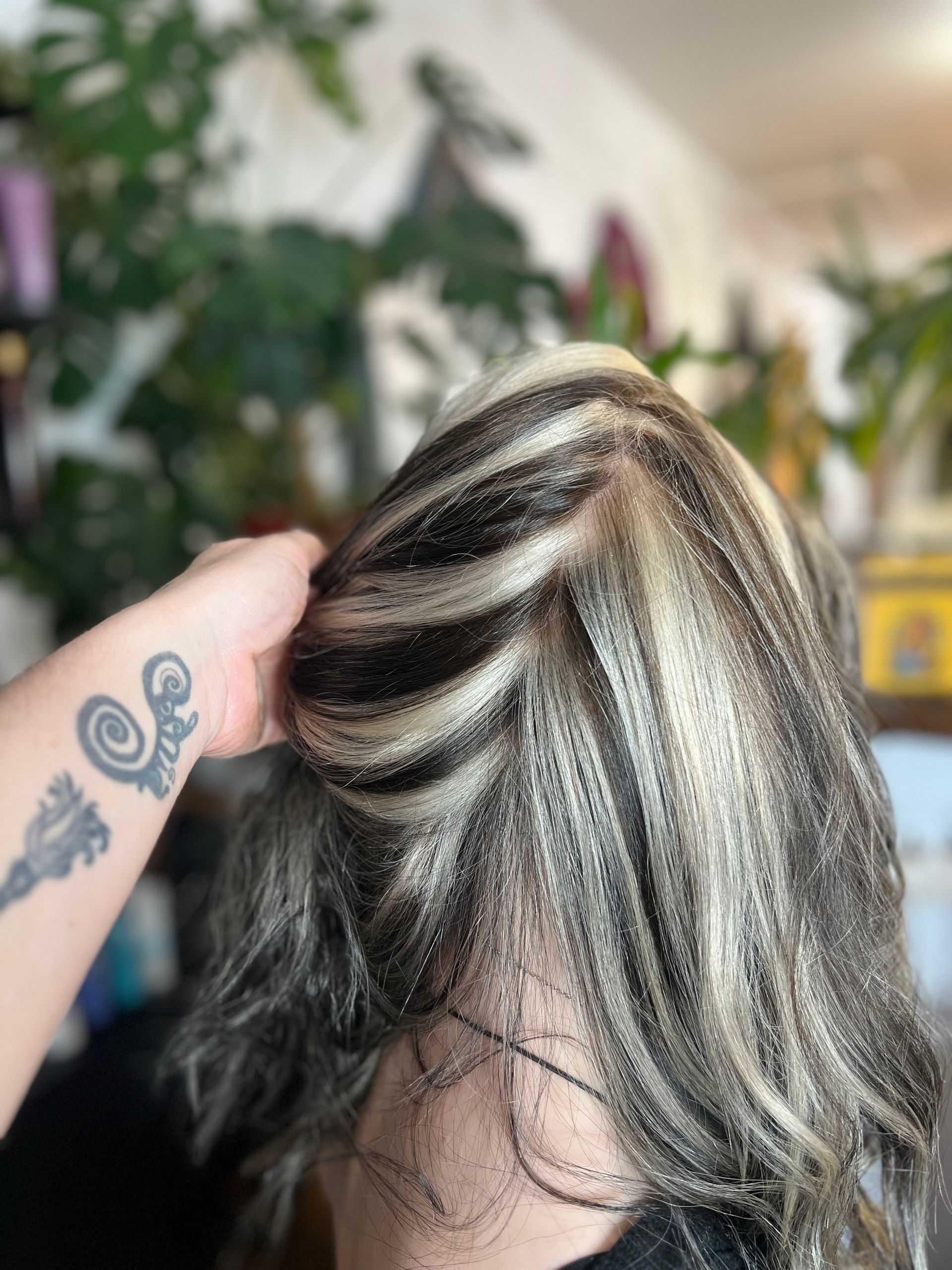 A person with a tattoo on their arm is touching a woman 's hair.