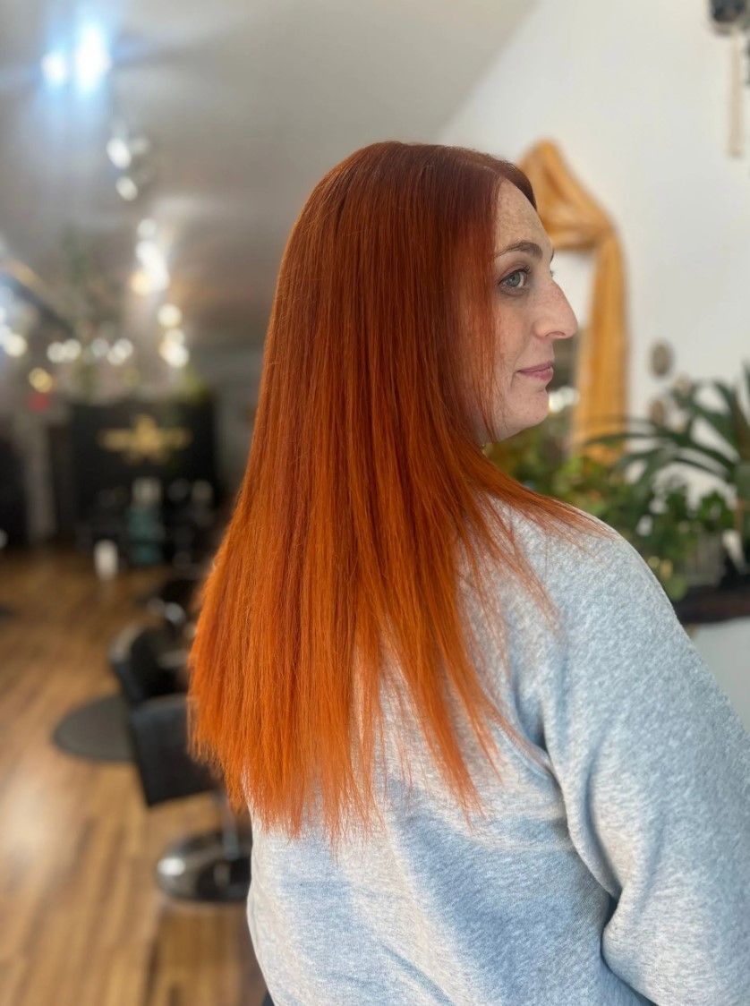 Long, straight, vibrant orange hair; person's back to camera; in a hair salon.