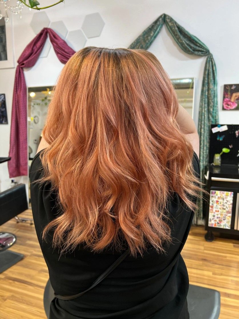 Person with long, wavy, copper-colored hair in a salon setting.