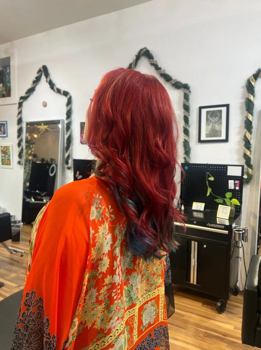 Person with wavy red hair and orange patterned kimono in a salon.