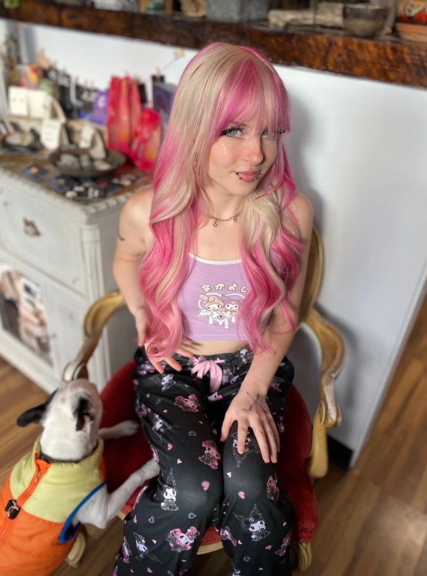 Woman with pink hair and a dog in pajamas.