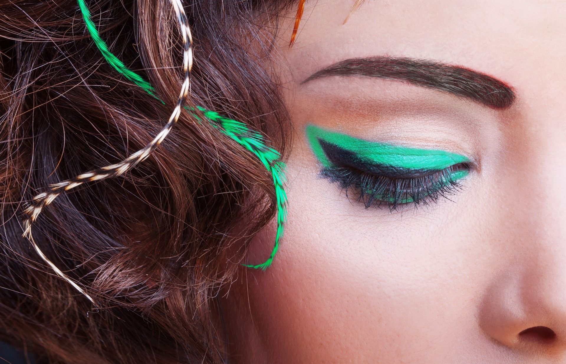 A close up of a woman 's face with green eye shadow.