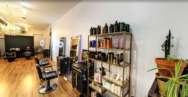 A salon with a lot of hair products on shelves and chairs.