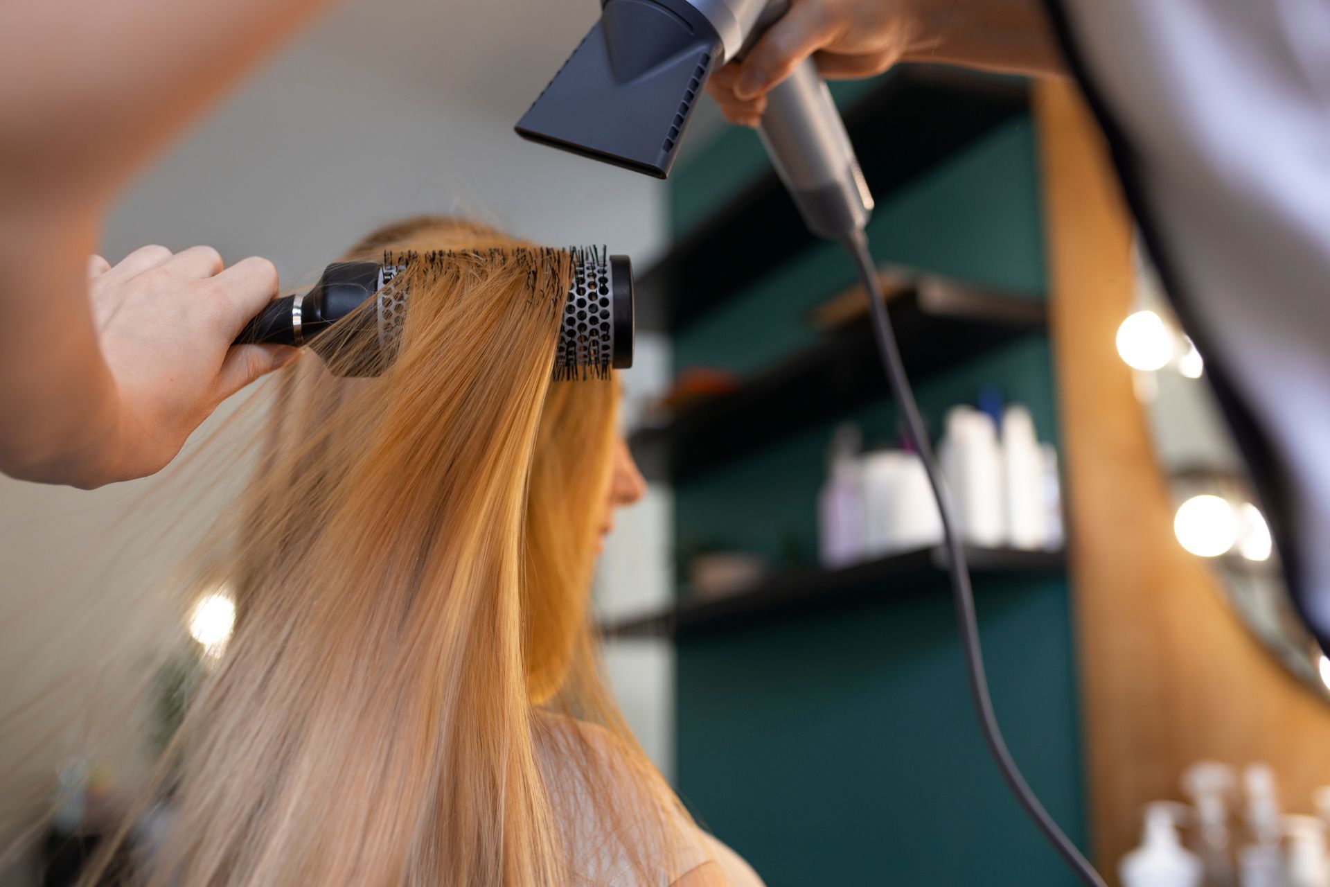 A woman is getting her hair blow dried by a hairdresser in a salon.