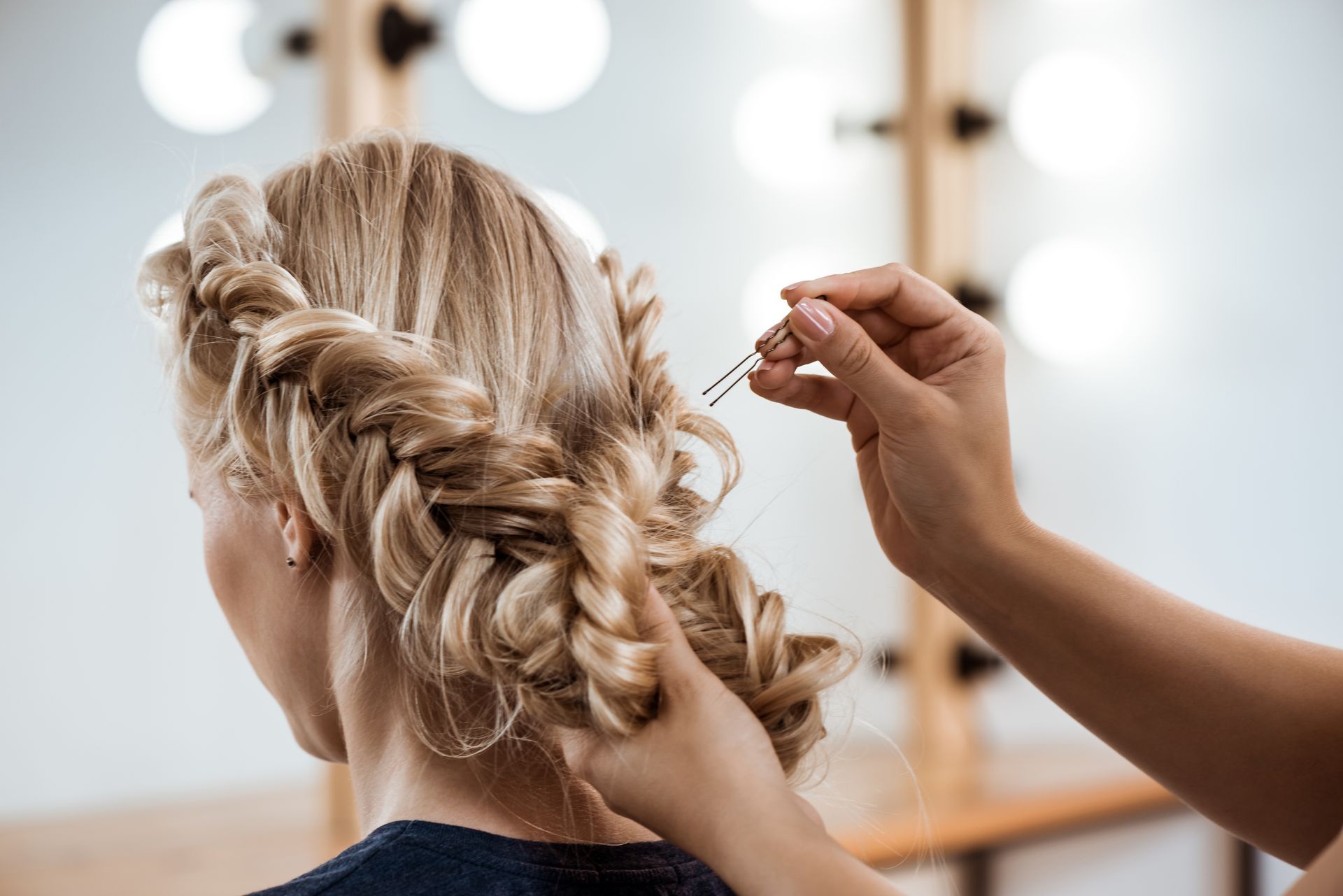 Blonde hair styled with braids, being styled with a hairpin.