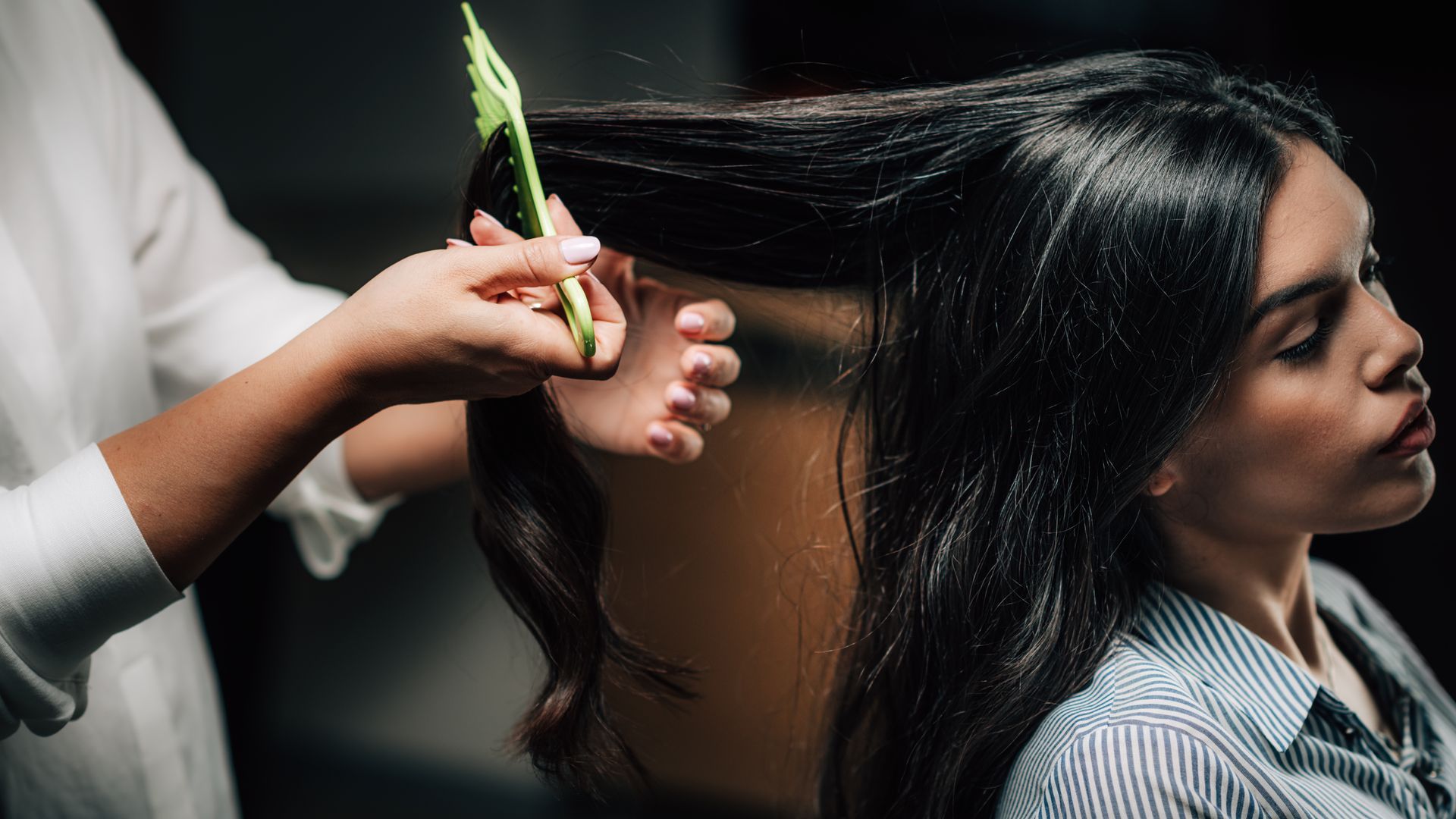 A woman is getting her hair done by a hairdresser in a salon.