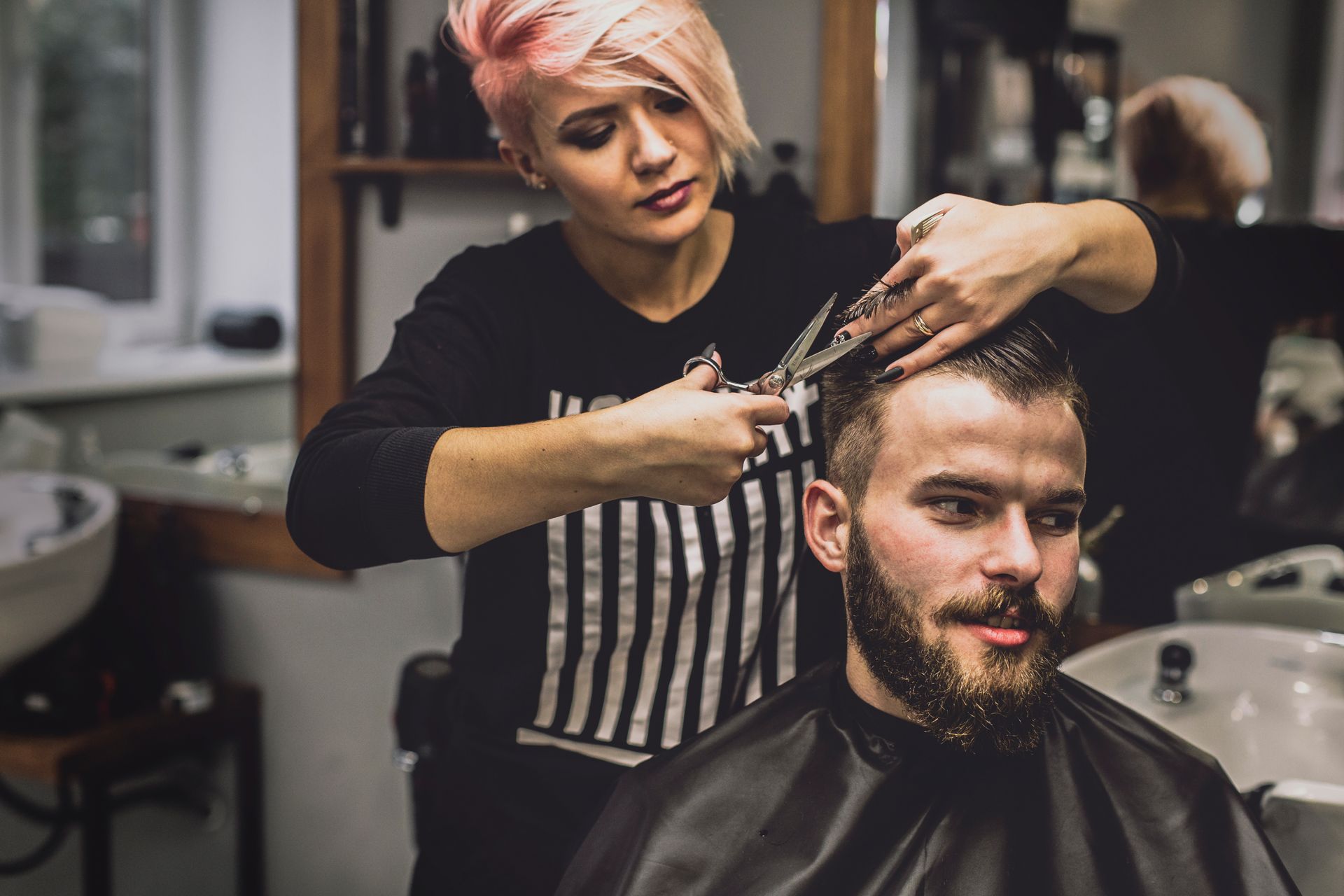 A woman is cutting a man 's hair in a barber shop.