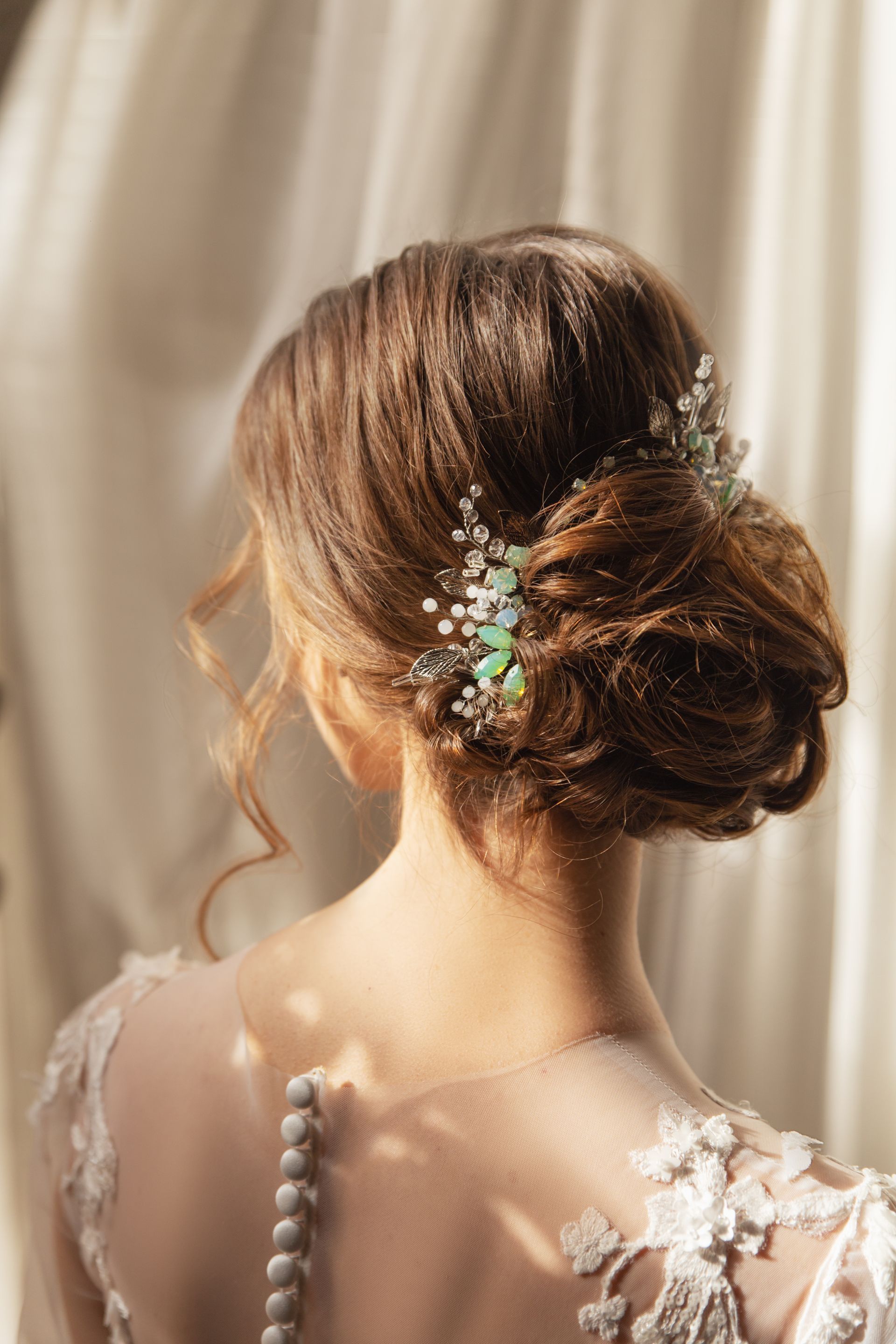 The back of a bride wearing a wedding dress and a bun with flowers in her hair.