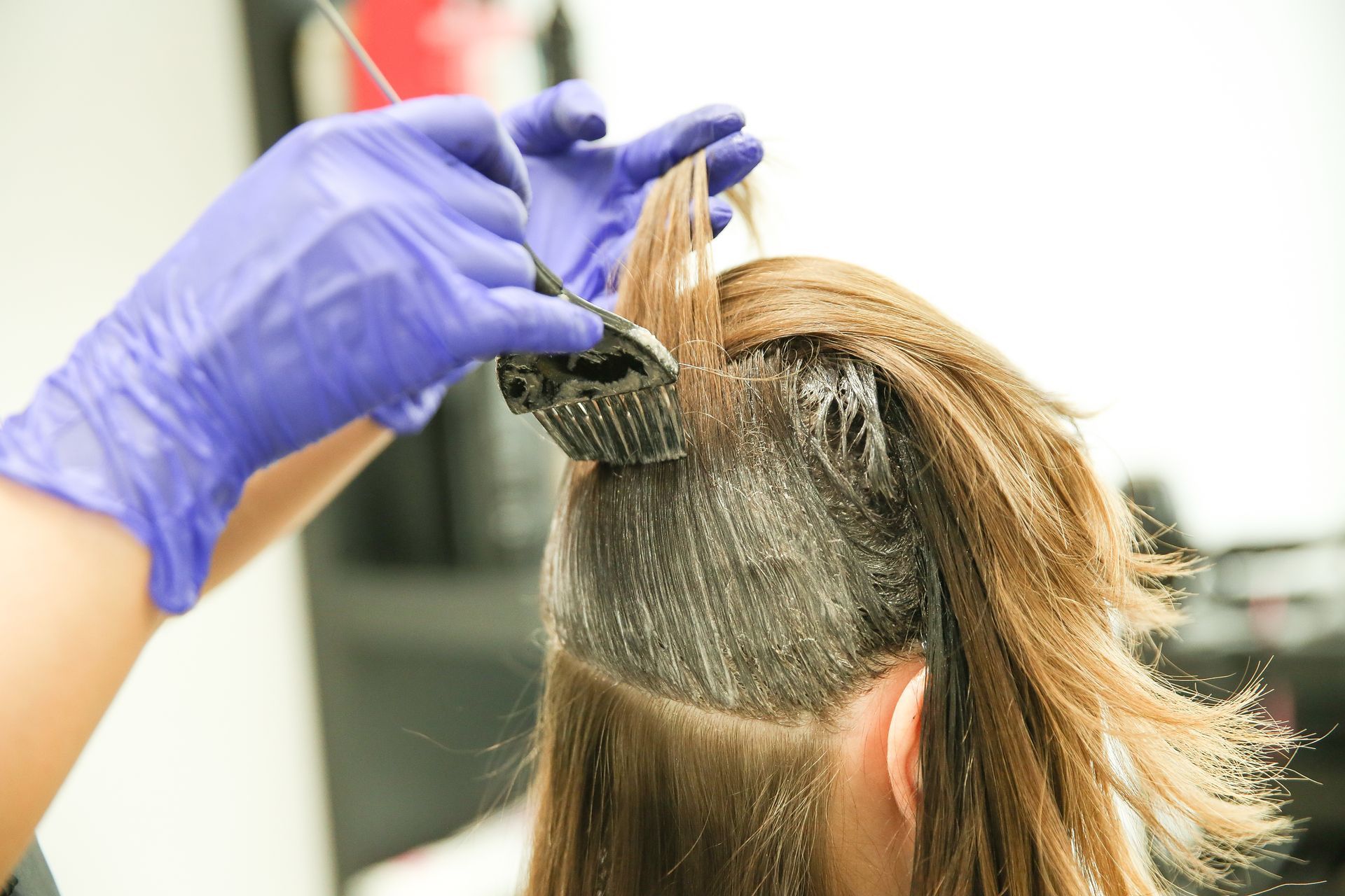 A woman is getting her hair dyed by a hairdresser in a salon.