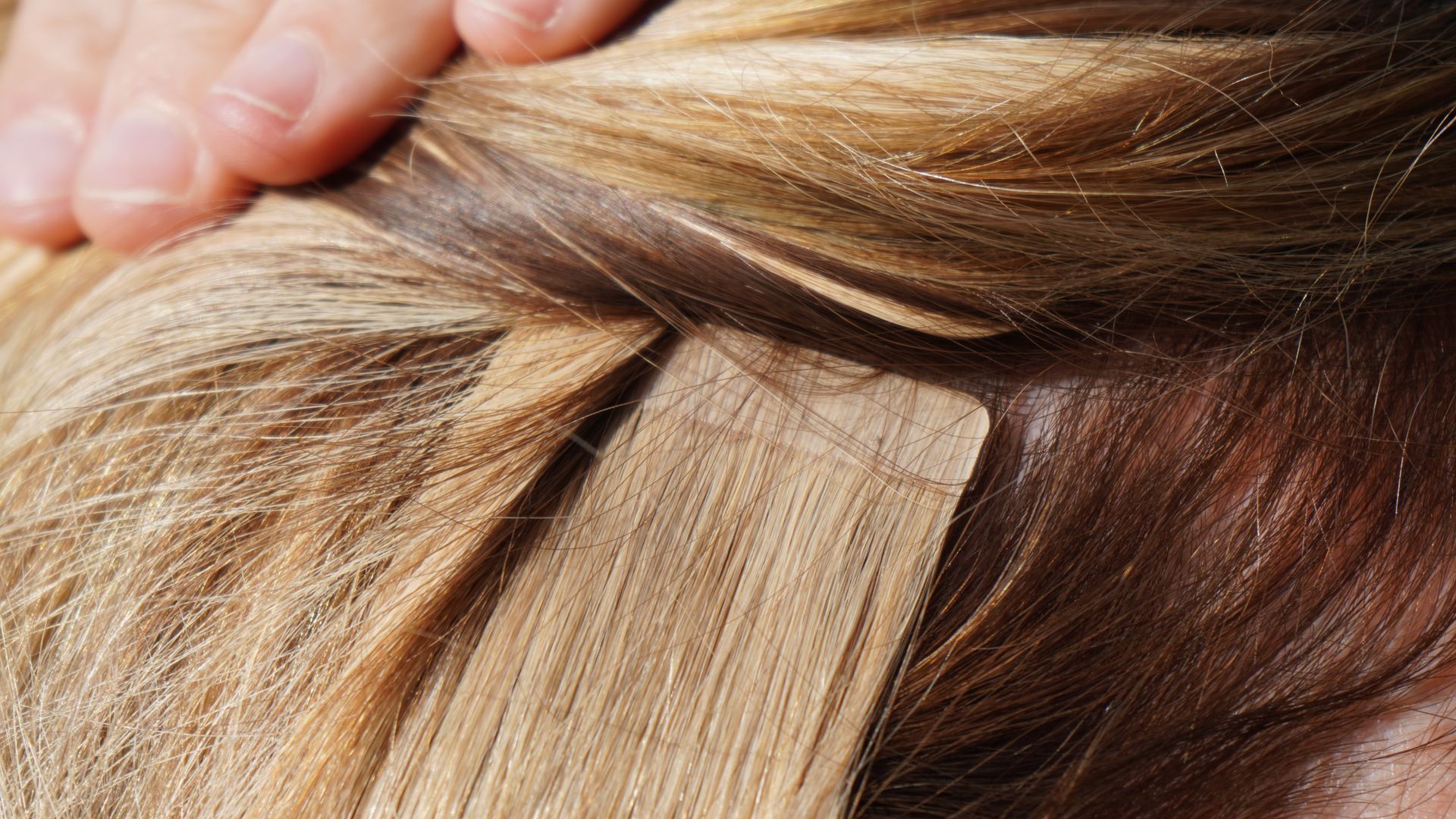 A close up of a woman 's hair extensions being applied to her head.