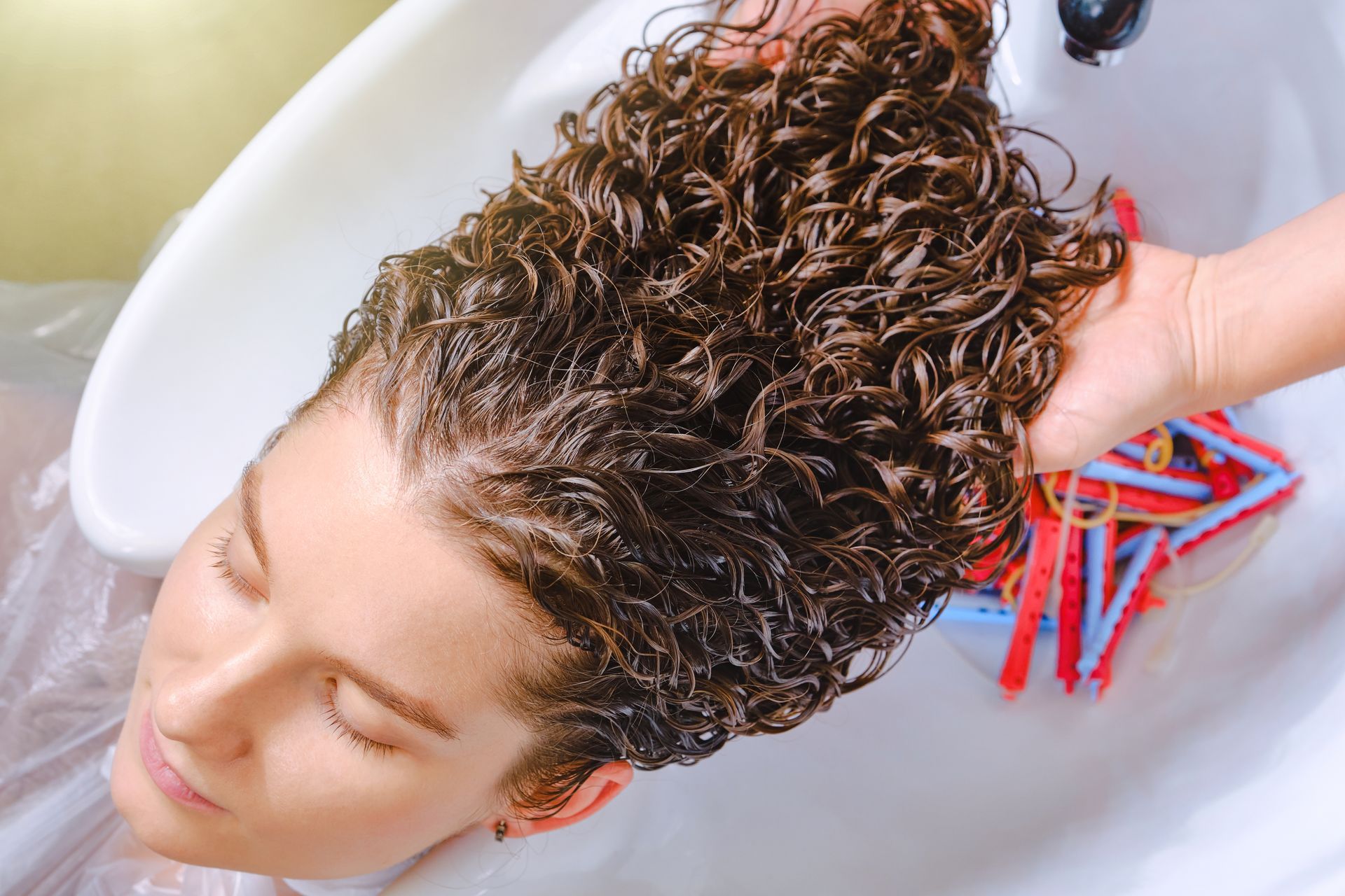 A woman is getting her hair washed in a sink.