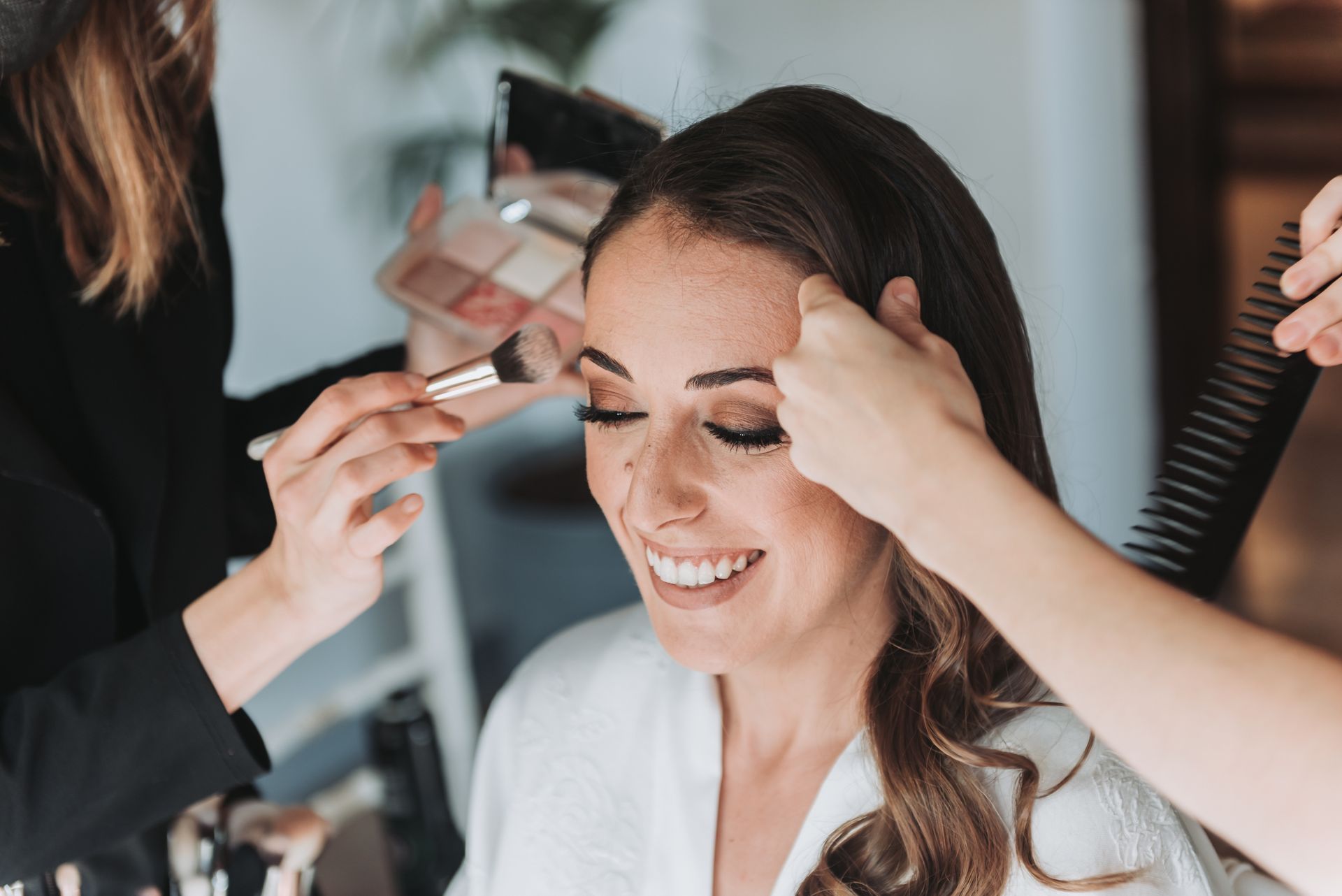 A woman is getting her hair done by a makeup artist.