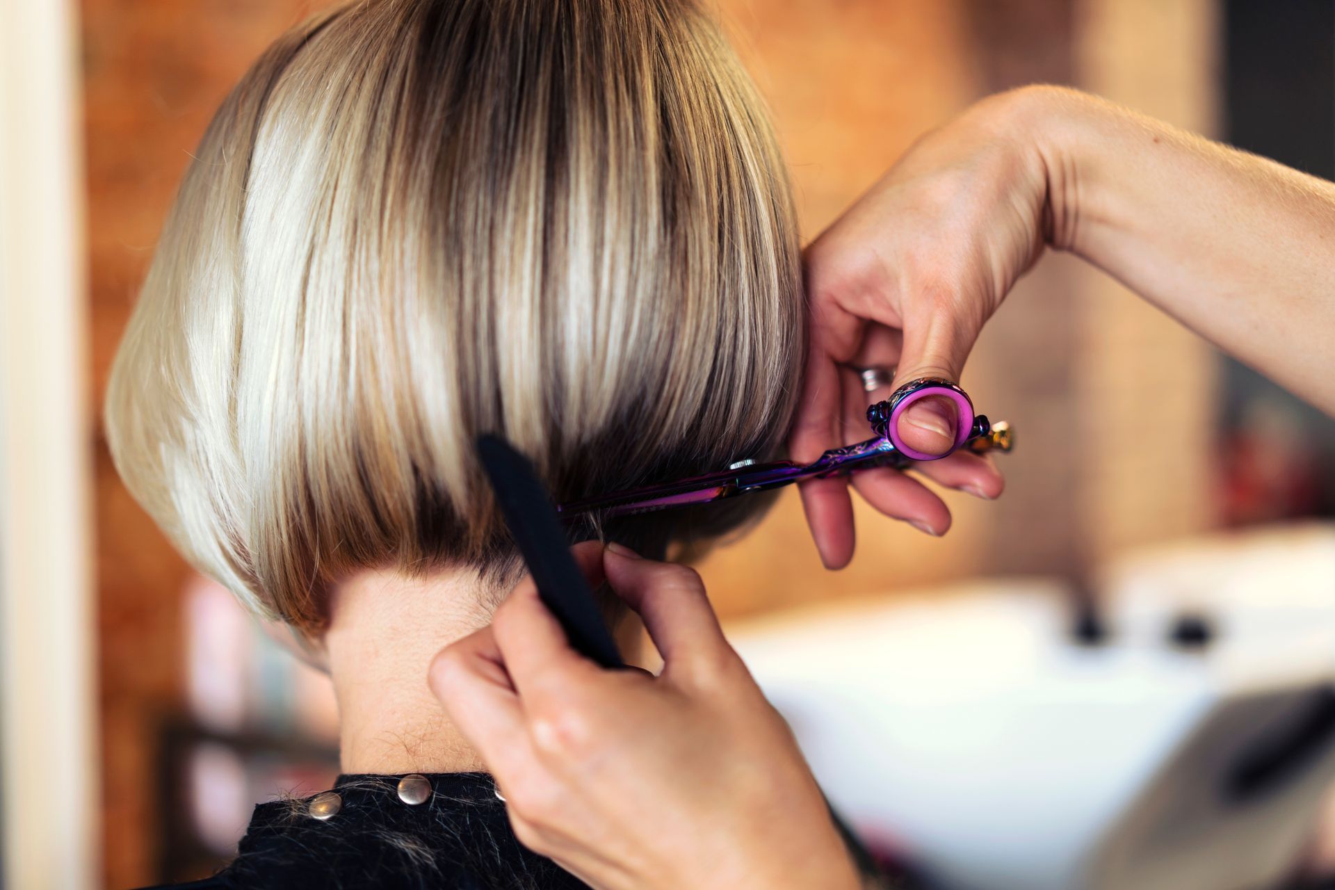 A woman is getting her hair cut by a hairdresser in a salon.