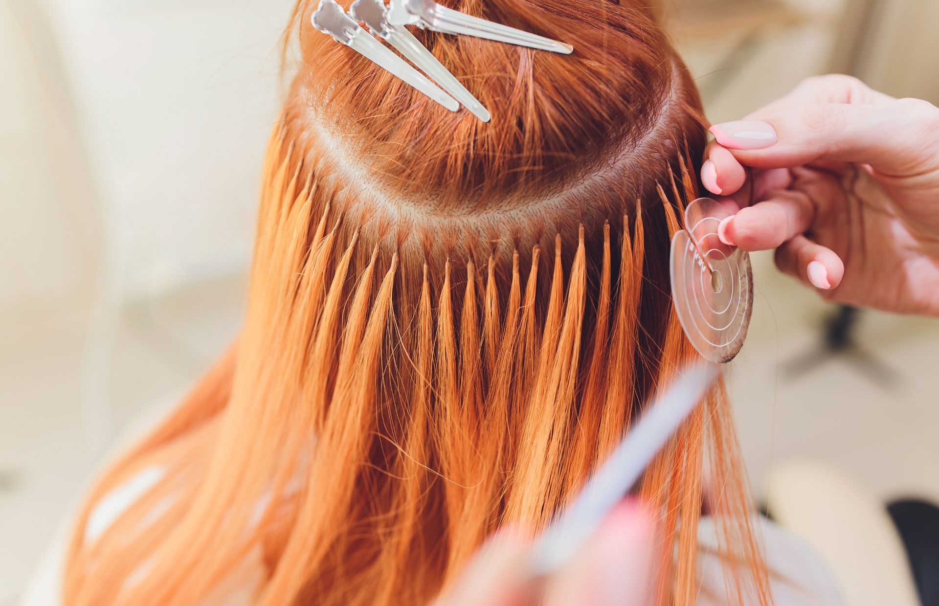 A woman is getting her hair extensions done by a hairdresser.