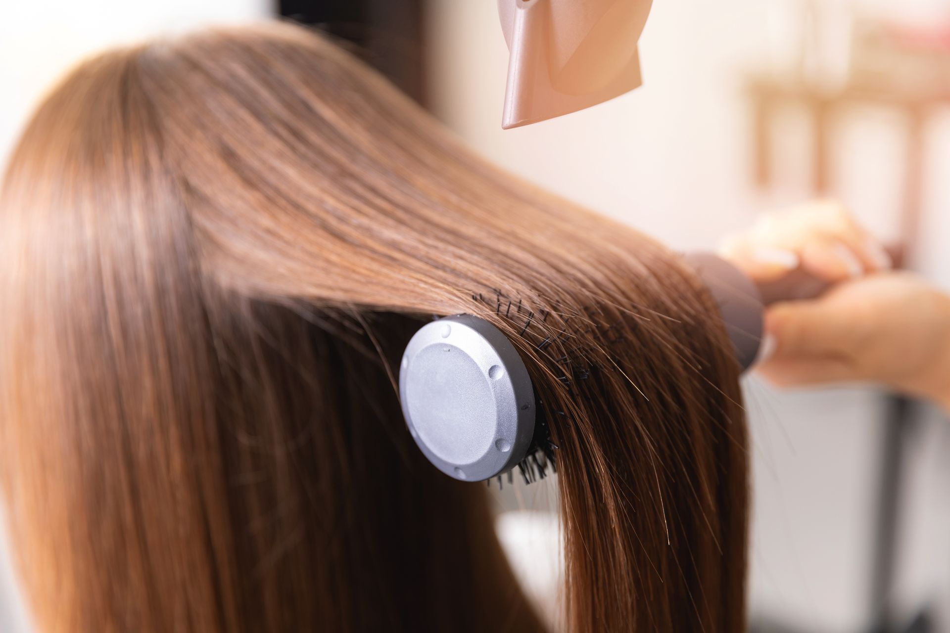Hair being styled with a round brush and a hairdryer.