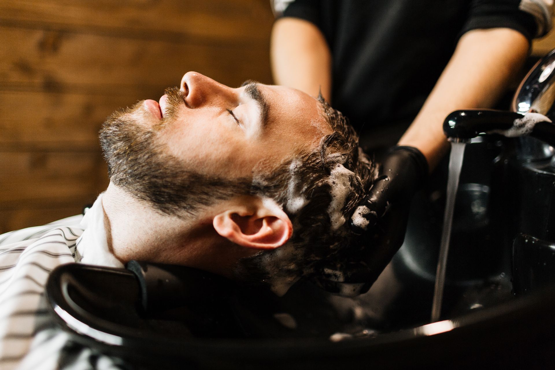 A man is getting his hair washed at a barber shop.